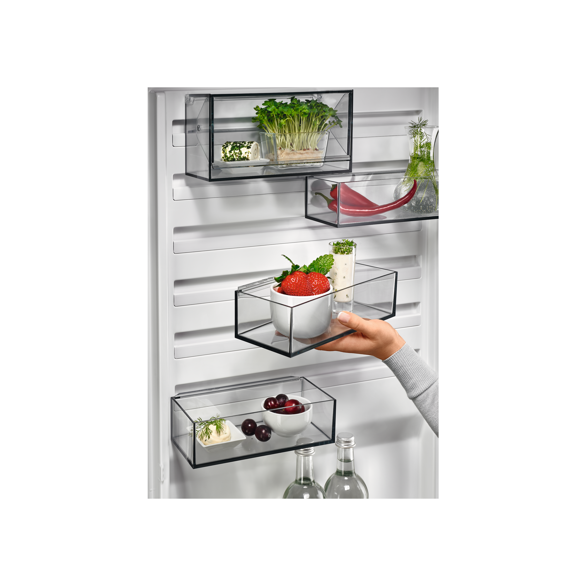 Wnętrze lodówki ze szklanymi półkami i produktami spożywczymi.