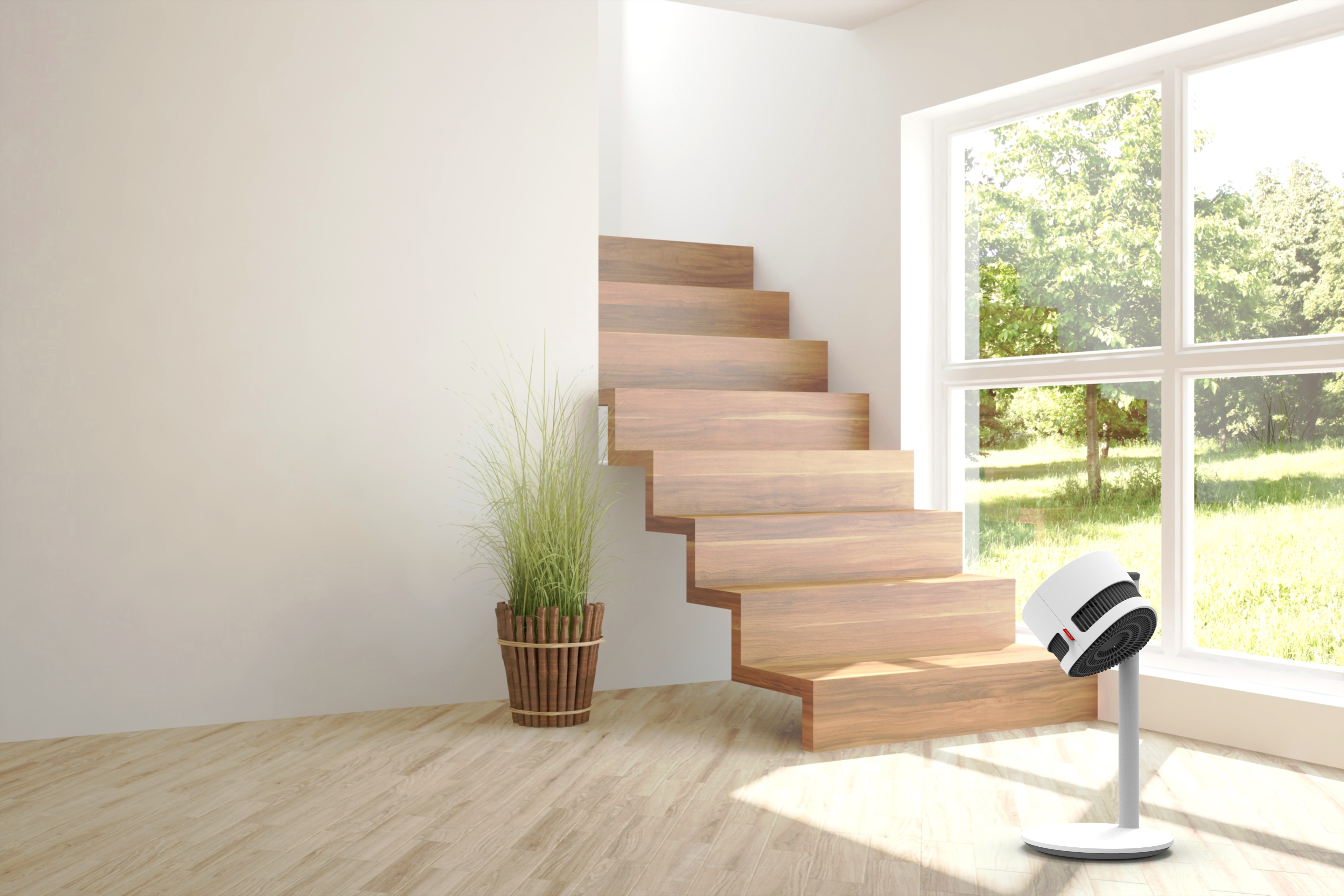 Un ventilateur blanc sur pied à côté d'un escalier en bois et d'une plante en pot.
