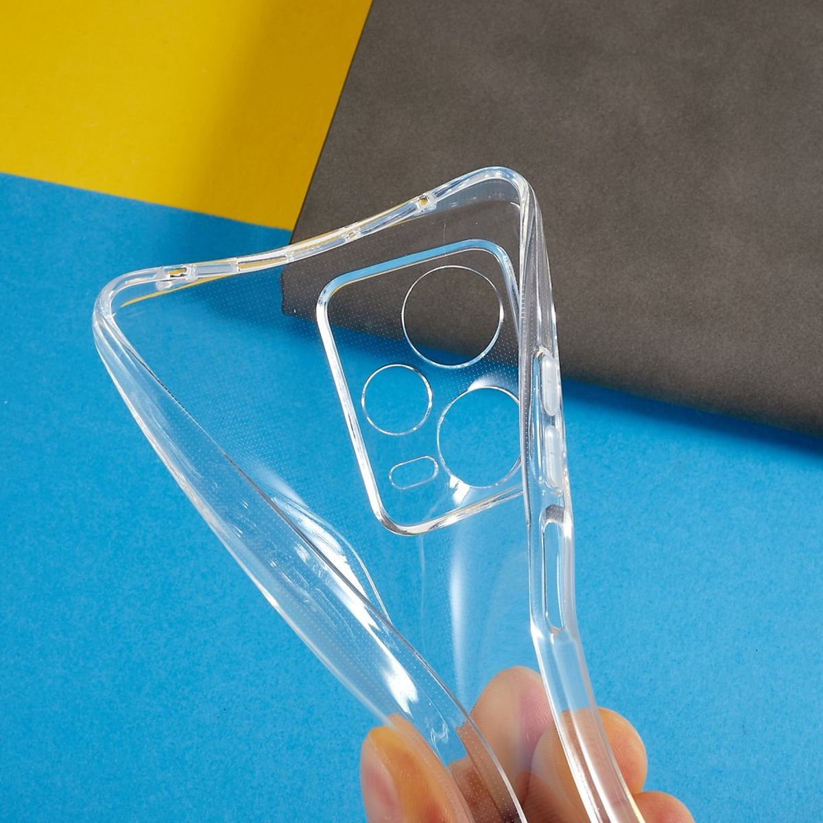 Eine transparente Handyhülle, gehalten von einer Hand, vor buntem Hintergrund. Kameraausschnitte.