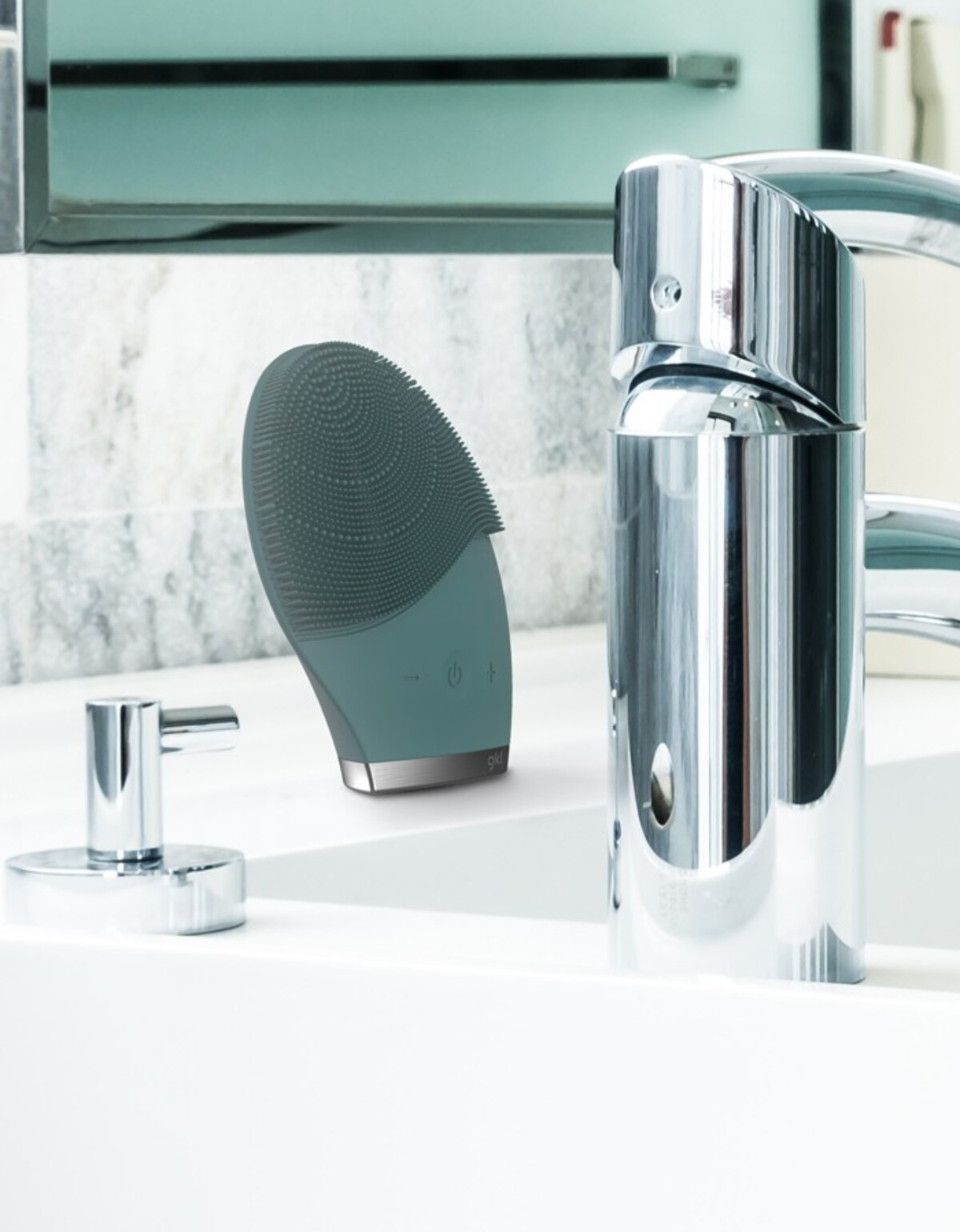 Un cepillo de limpieza facial y un grifo en un baño.