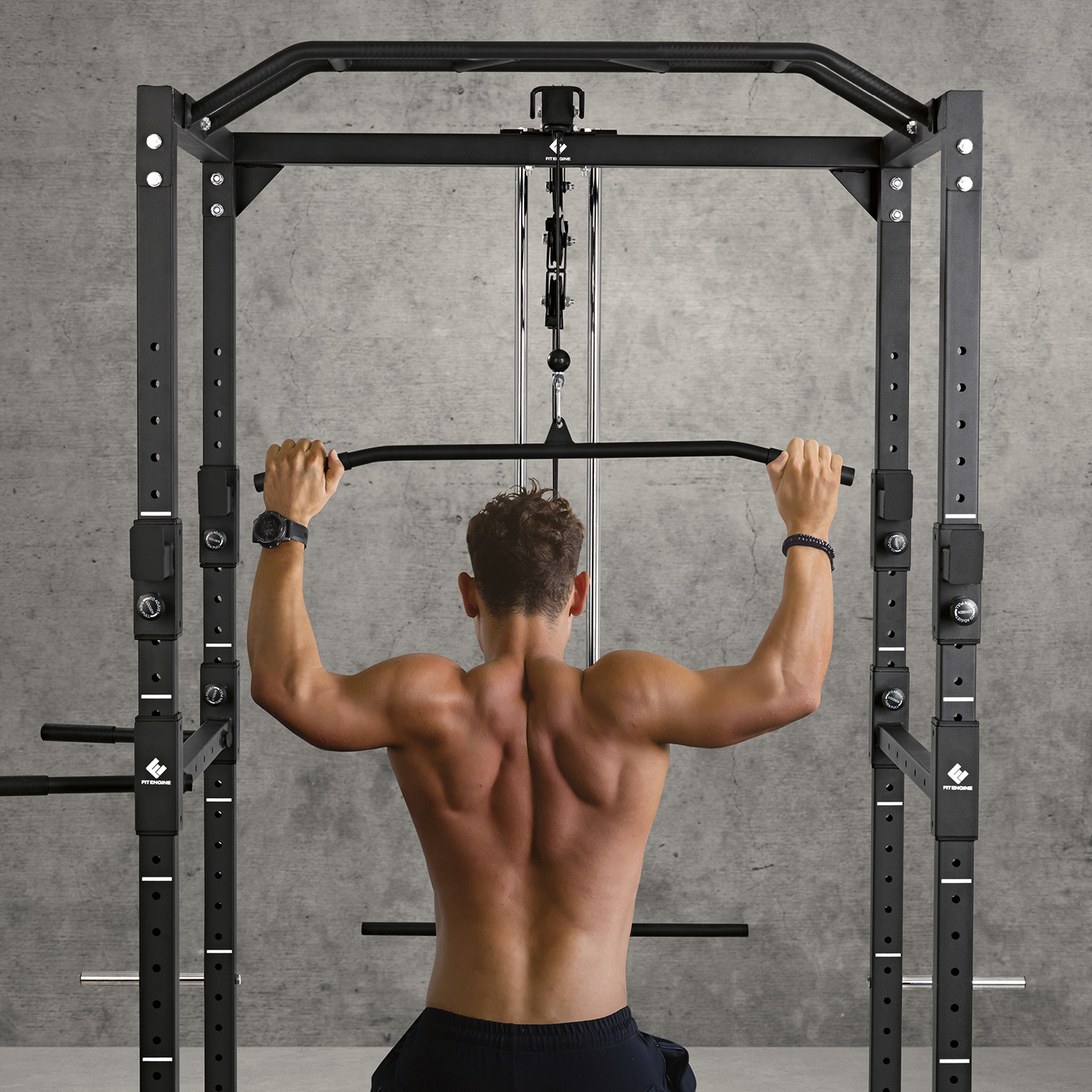 Mann, der Klimmzüge an einem schwarzen Power Rack in einem Fitnessstudio macht. Der Mann ist ohne Hemd.