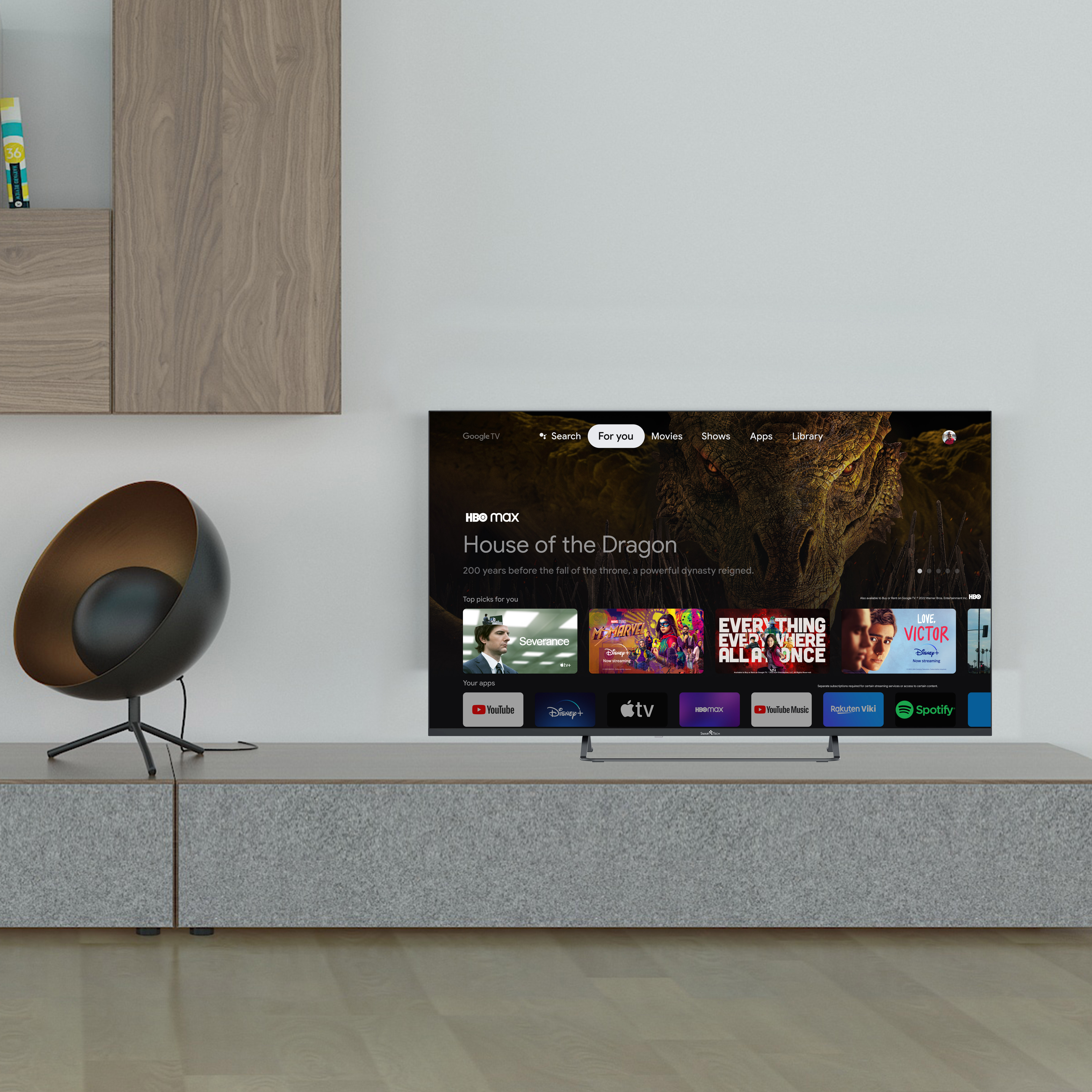 Telewizor wyświetla 'House of the Dragon', na szarej szafce. Czarny fotel po lewej.