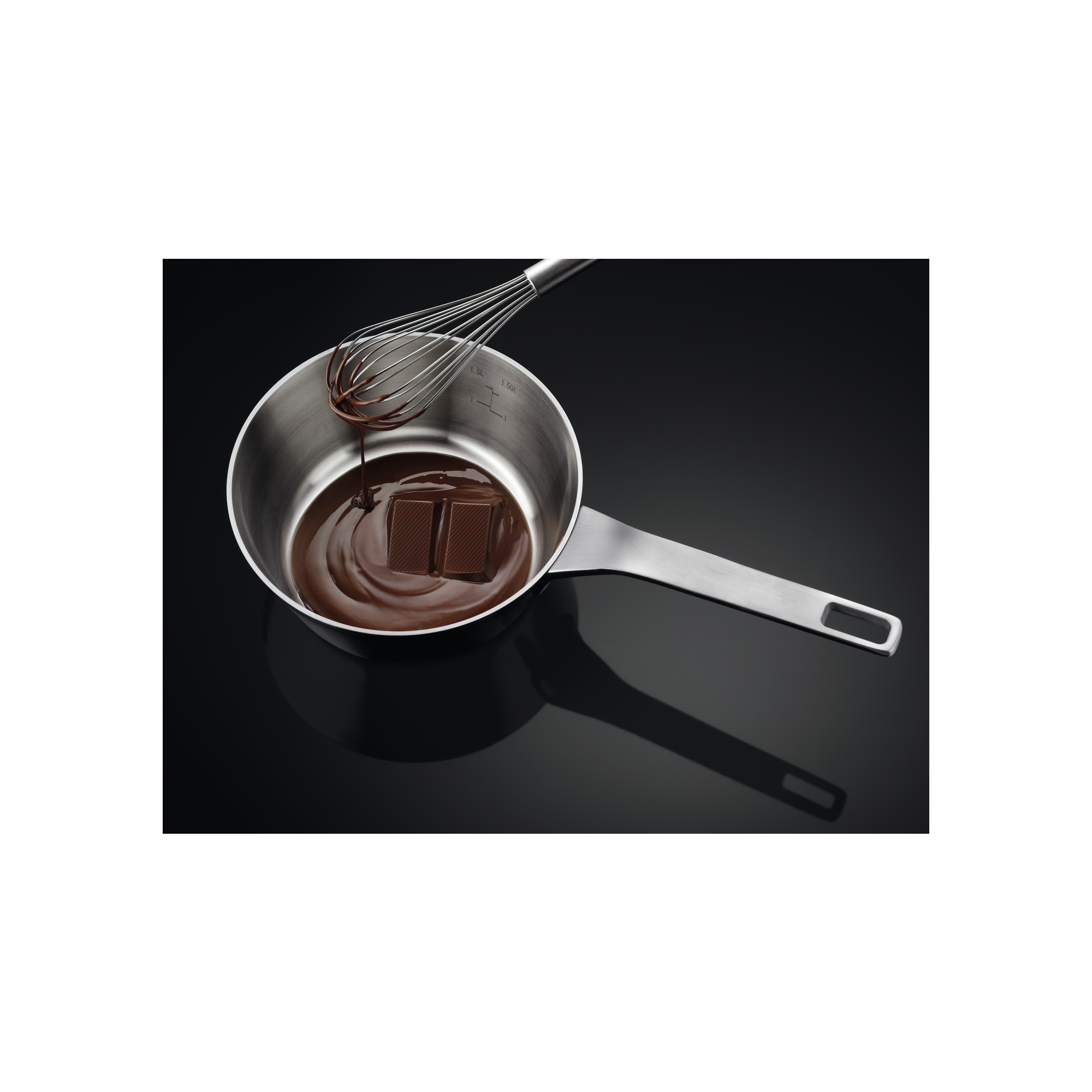 Een roestvrijstalen steelpan met gesmolten chocolade en een garde, op een zwarte achtergrond.