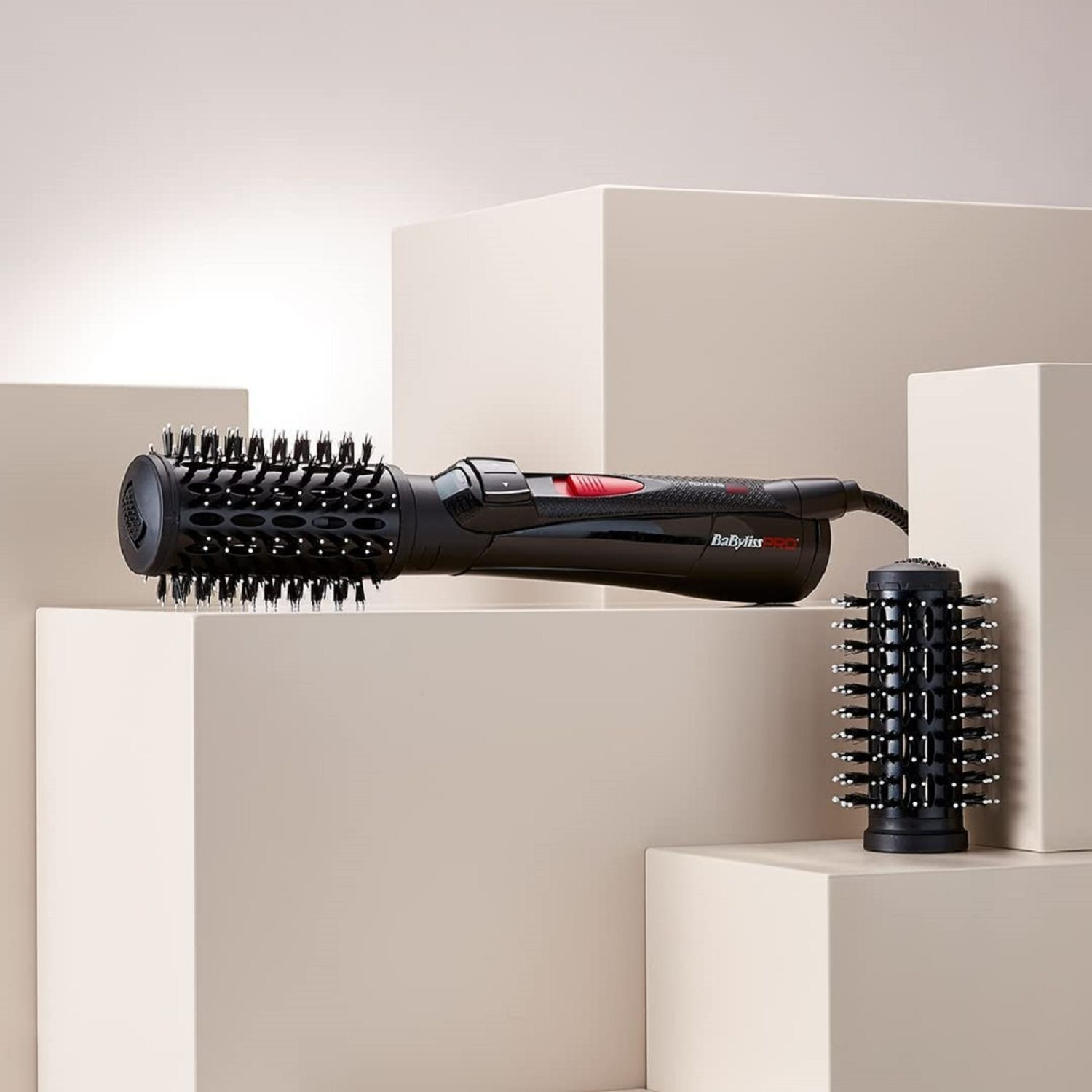 Schwarze Haarbürste mit zwei Aufsätzen auf neutralem Hintergrund.