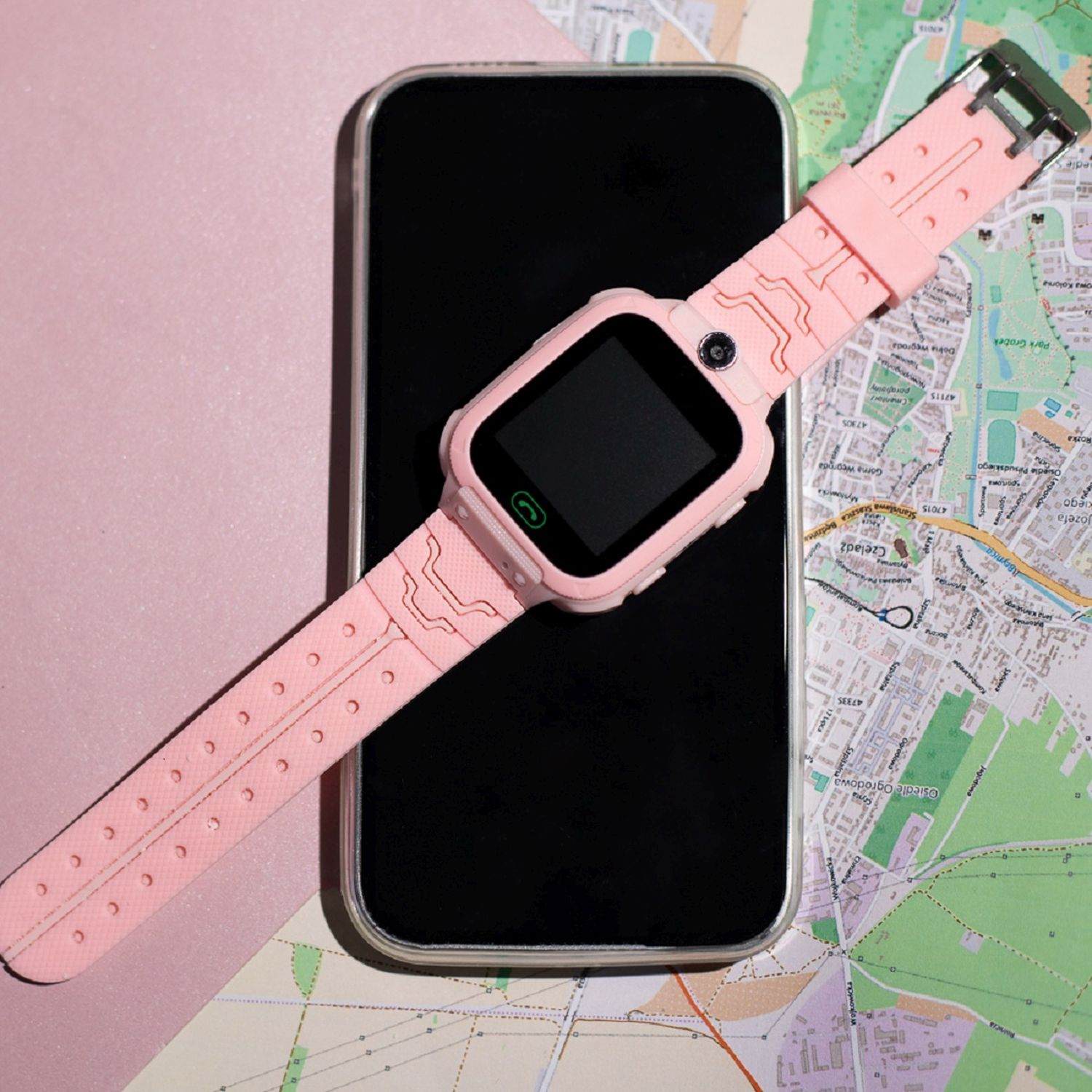 Rosa Smartwatch auf einem schwarzen Telefon, das auf einer Karte liegt.