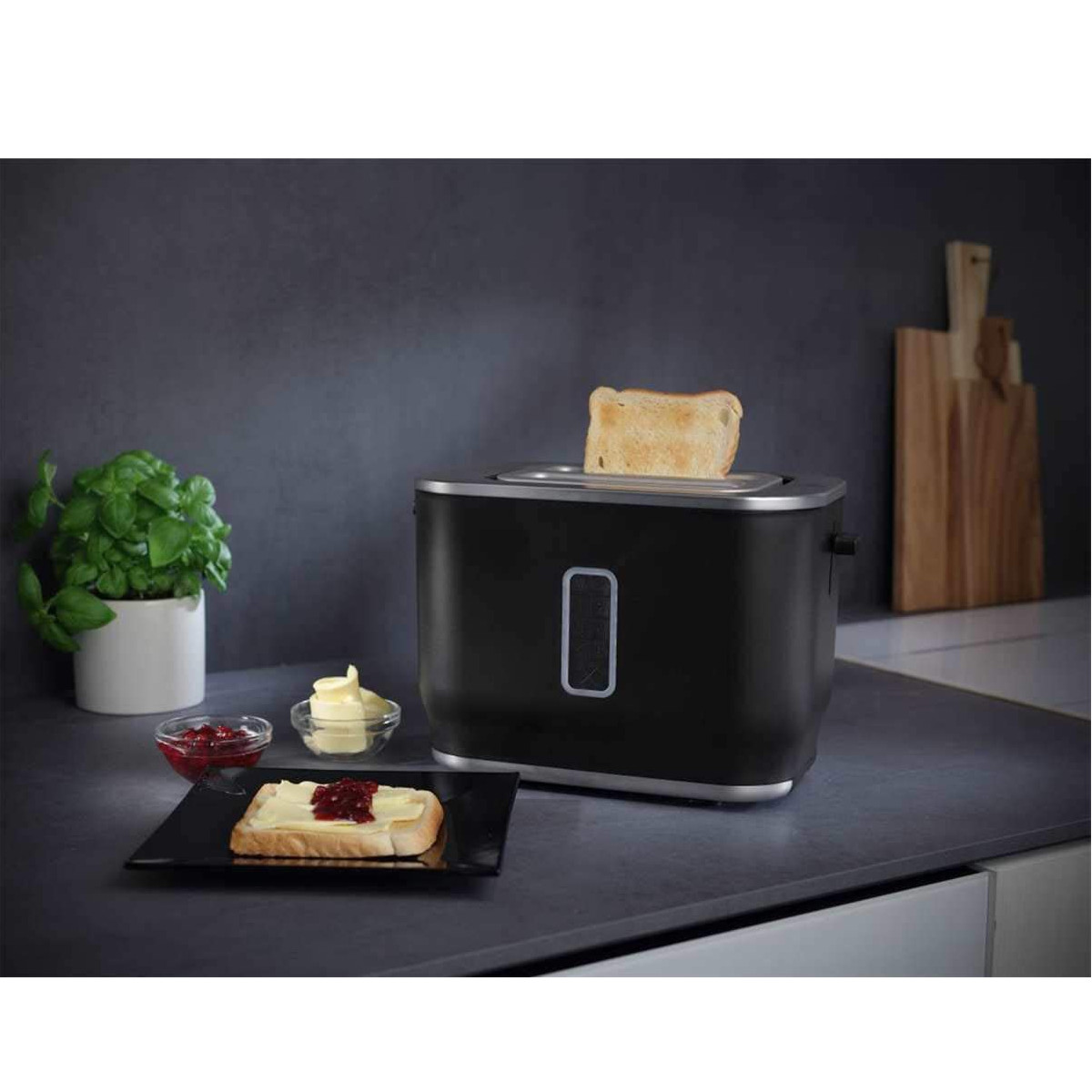 Ein Toaster mit herausgebackenem Toast und Zubehör auf einer Theke.