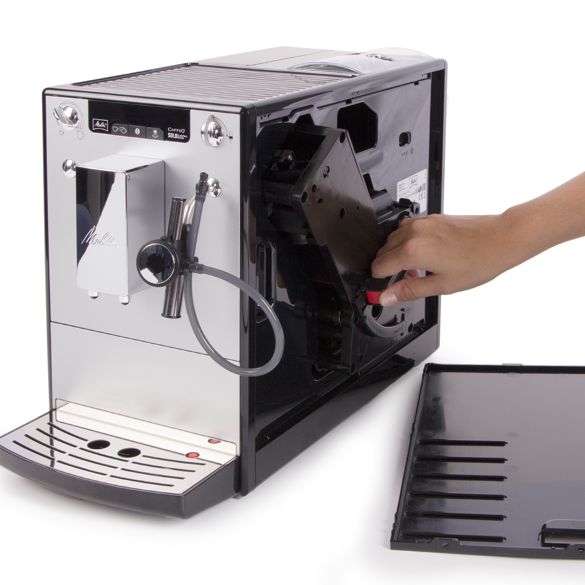 Eine silberne und schwarze Kaffeemaschine wird zerlegt. Eine Hand entfernt eine schwarze interne Komponente.