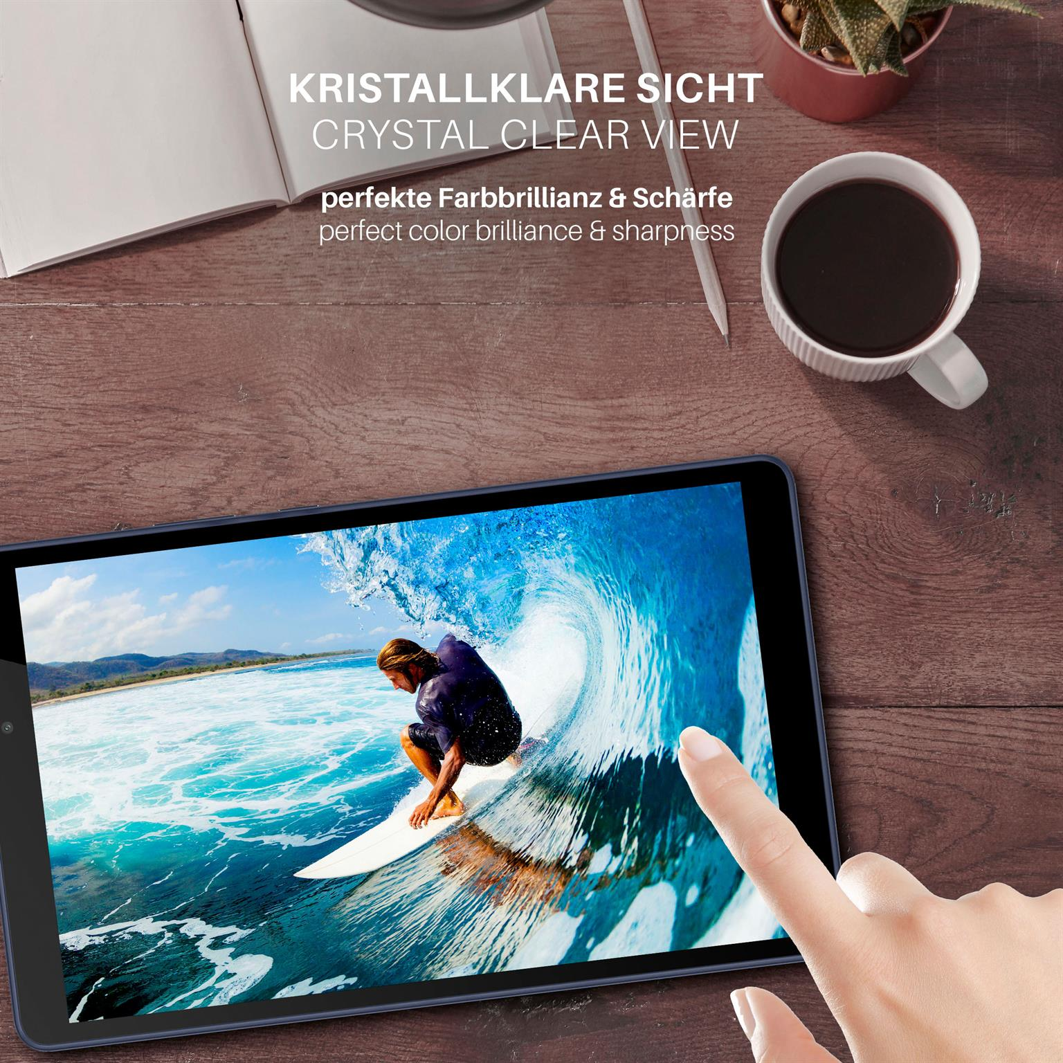 Person hält Tablet mit Surfbild. Kaffeetasse und Stift auf dem Tisch.