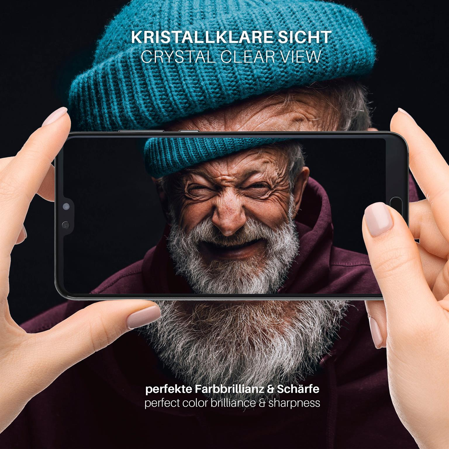 Eine Person hält ein Telefon, das einen lächelnden älteren Mann mit blauem Hut und weißem Bart zeigt.