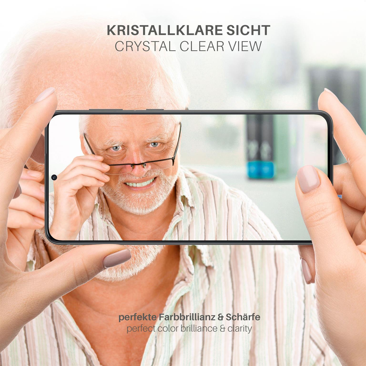 Ein Mann hält ein Telefon und schaut es an. Das Telefon zeigt ein Bild des Mannes. Fokus auf Gesicht und Brille.