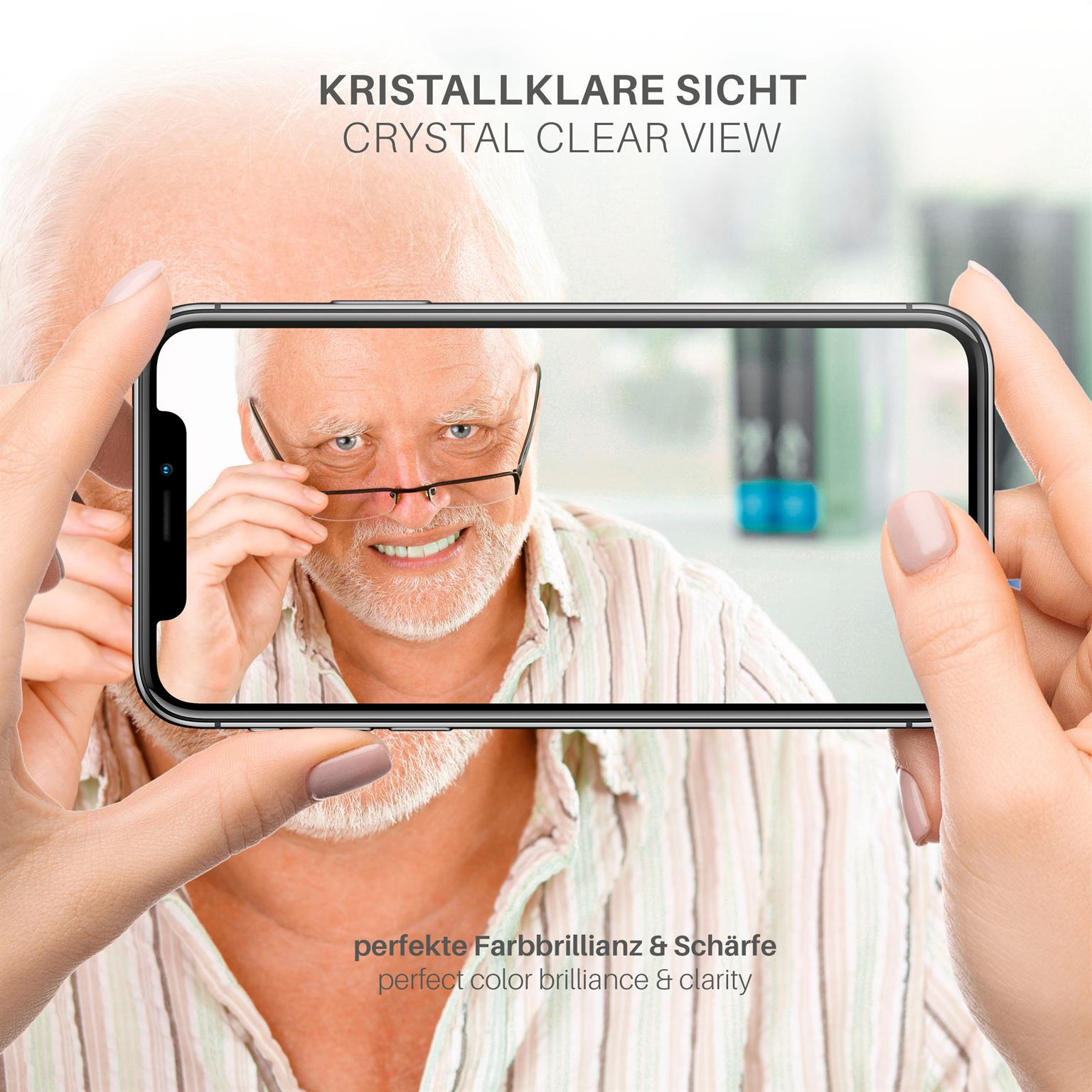 Eine Person hält ein Telefon, das das Gesicht eines älteren Mannes zeigt. Der Text besagt 'kristallklare Sicht' und Farbbrillanz.