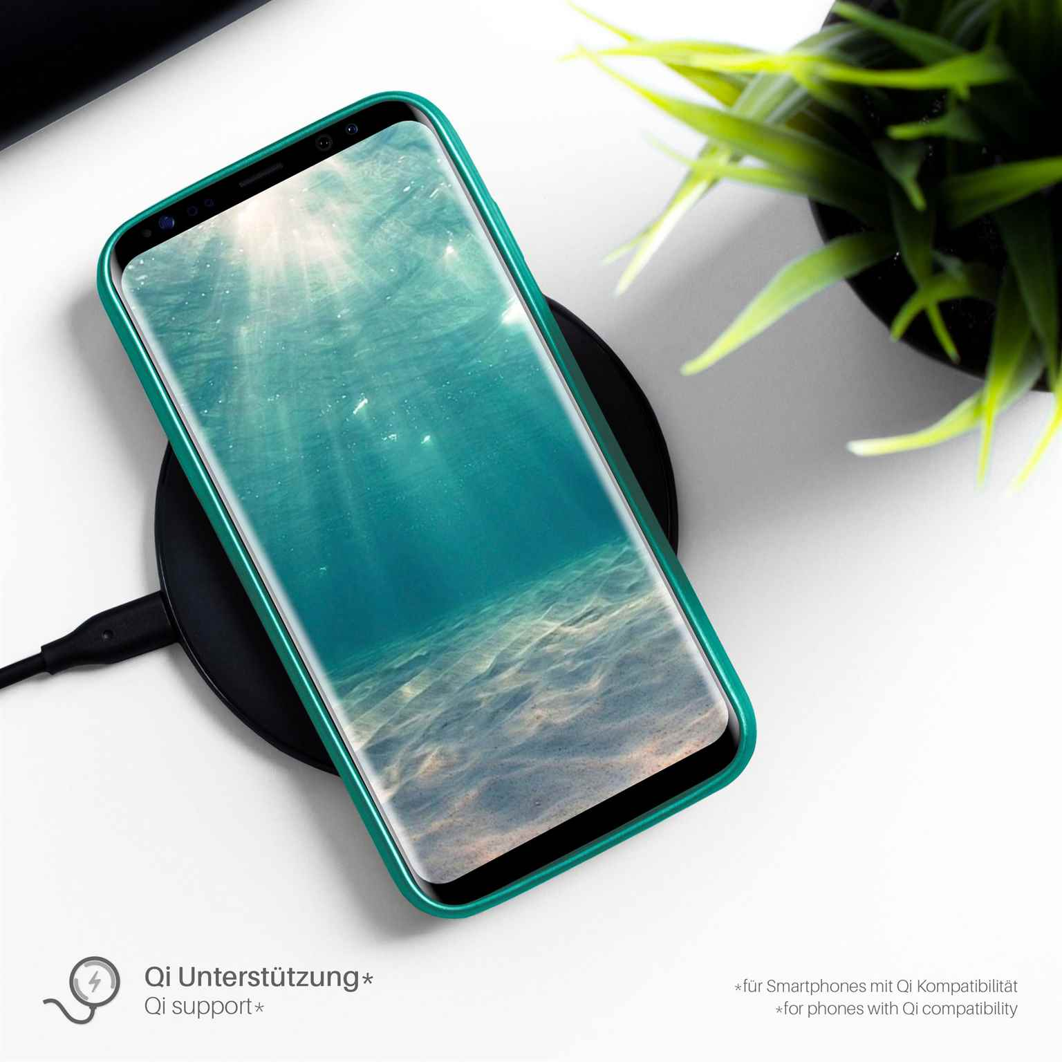 Ein Telefon mit grüner Hülle, drahtlos auf einem schwarzen Pad ladend.