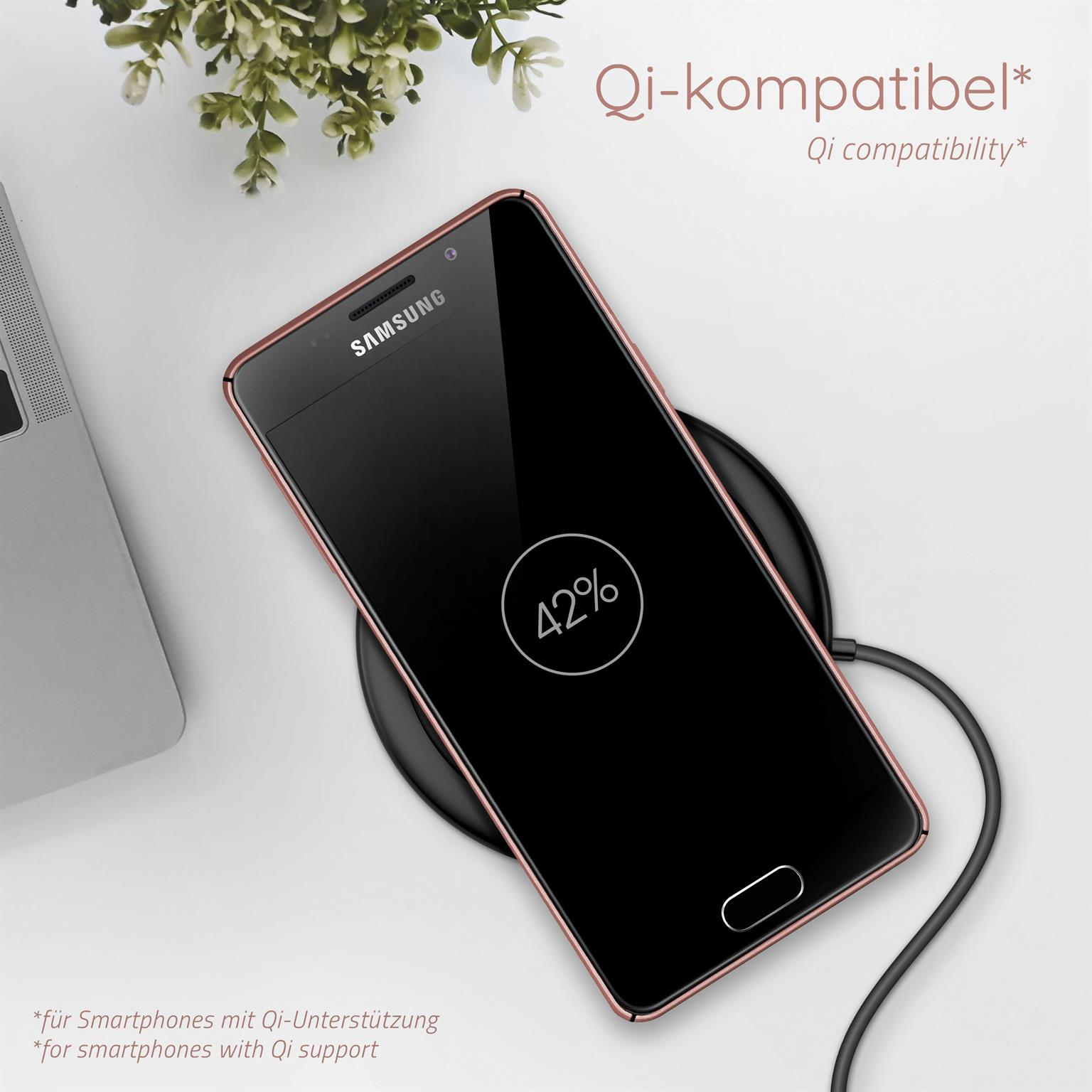 Rosa Telefon auf Ladegerät zeigt 42%. Rosa Rahmen. Kleine Pflanze im Hintergrund.