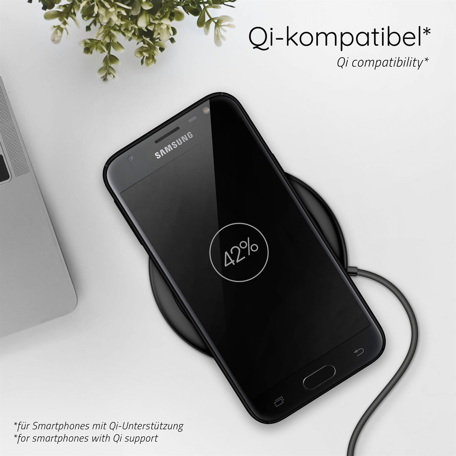 Schwarzes Telefon auf einem kabellosen Ladegerät, zeigt 42% Akku. Eine Pflanze daneben.