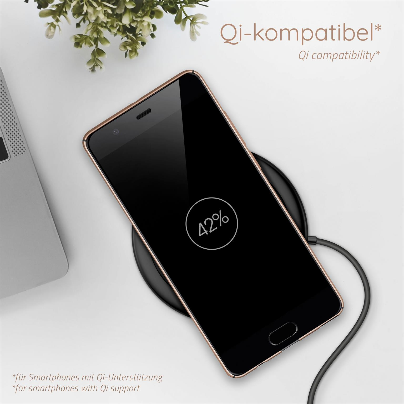 Telefon auf kabellosem Ladegerät mit 42% Akku. Weißer Tisch, grüne Pflanze im Hintergrund.