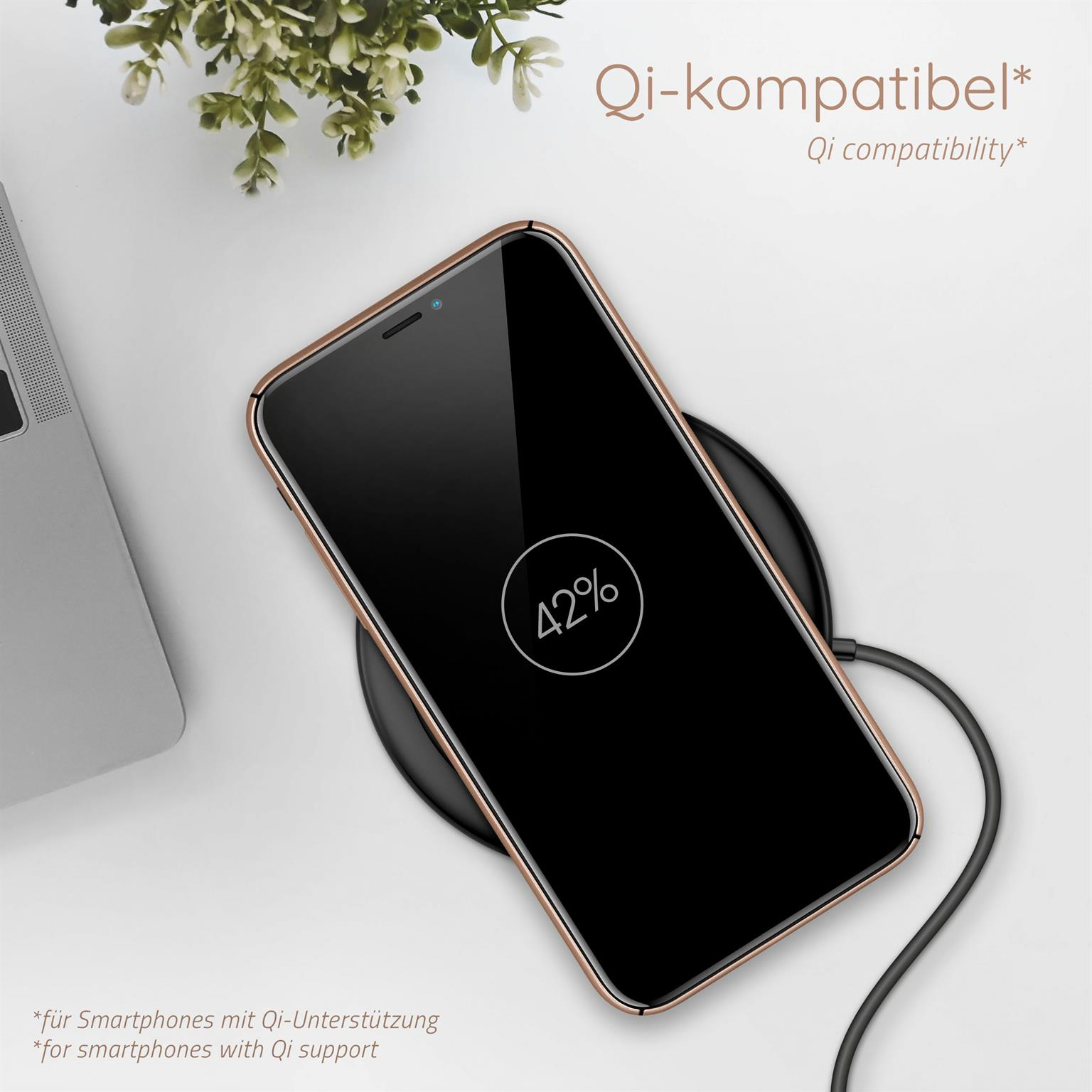 Telefon lädt auf einem kabellosen Ladegerät. Das Telefon hat einen schwarzen Bildschirm mit 42 %. Eine Pflanze im Hintergrund.