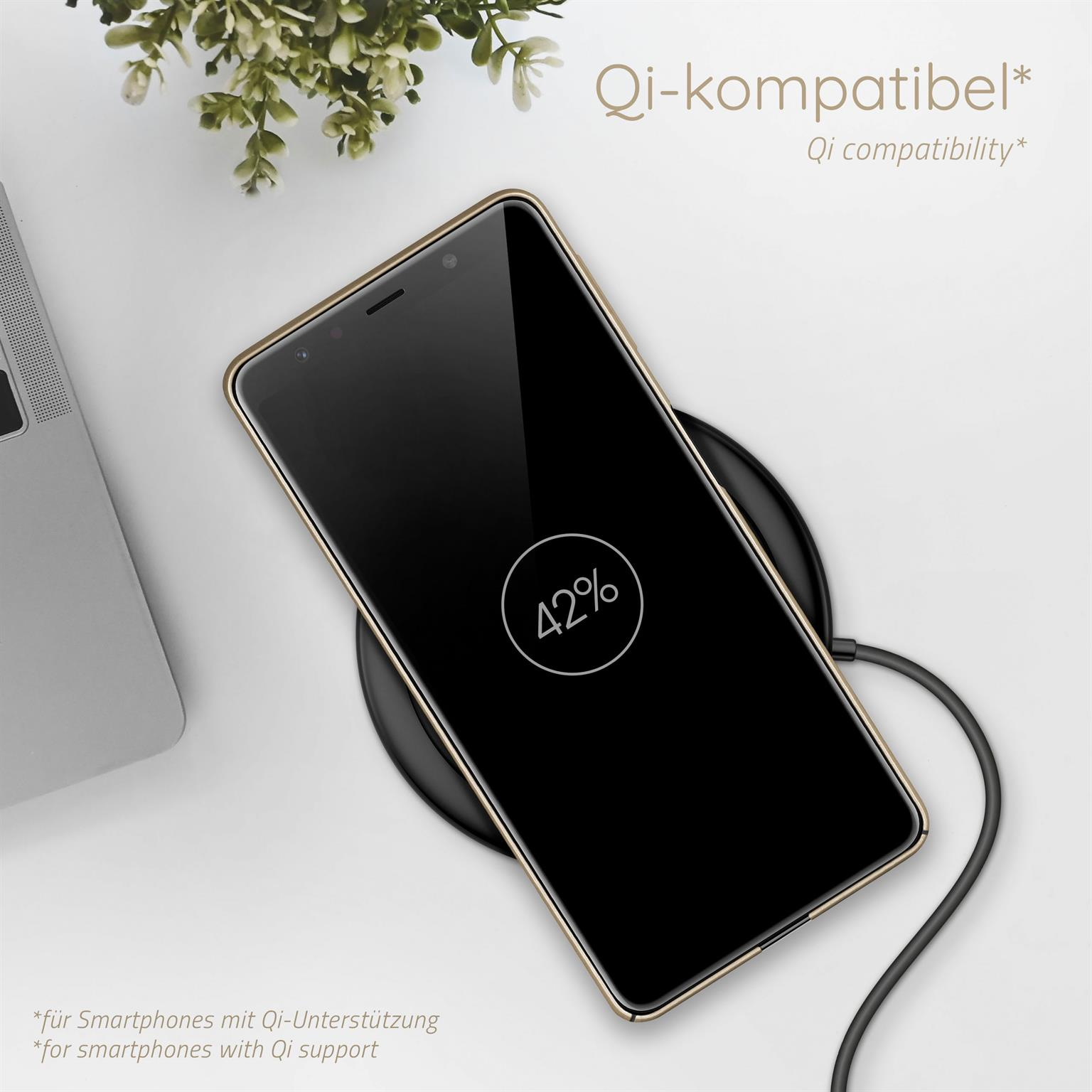 Telefon auf schwarzem Ladepad, 42% Ladung. Hintergrund: Laptop & weiße Oberfläche.