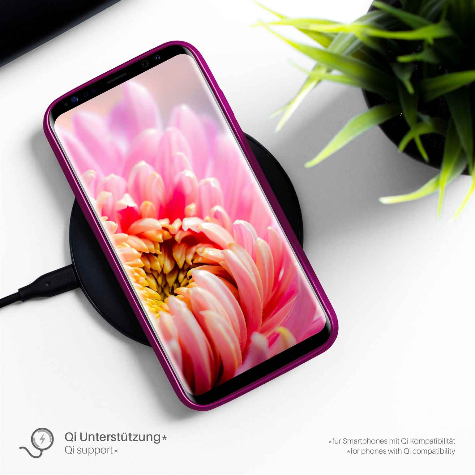Ein Telefon in einer lila Hülle liegt auf einem kabellosen Ladegerät. Das Telefon zeigt ein rosa Blumenbild.
