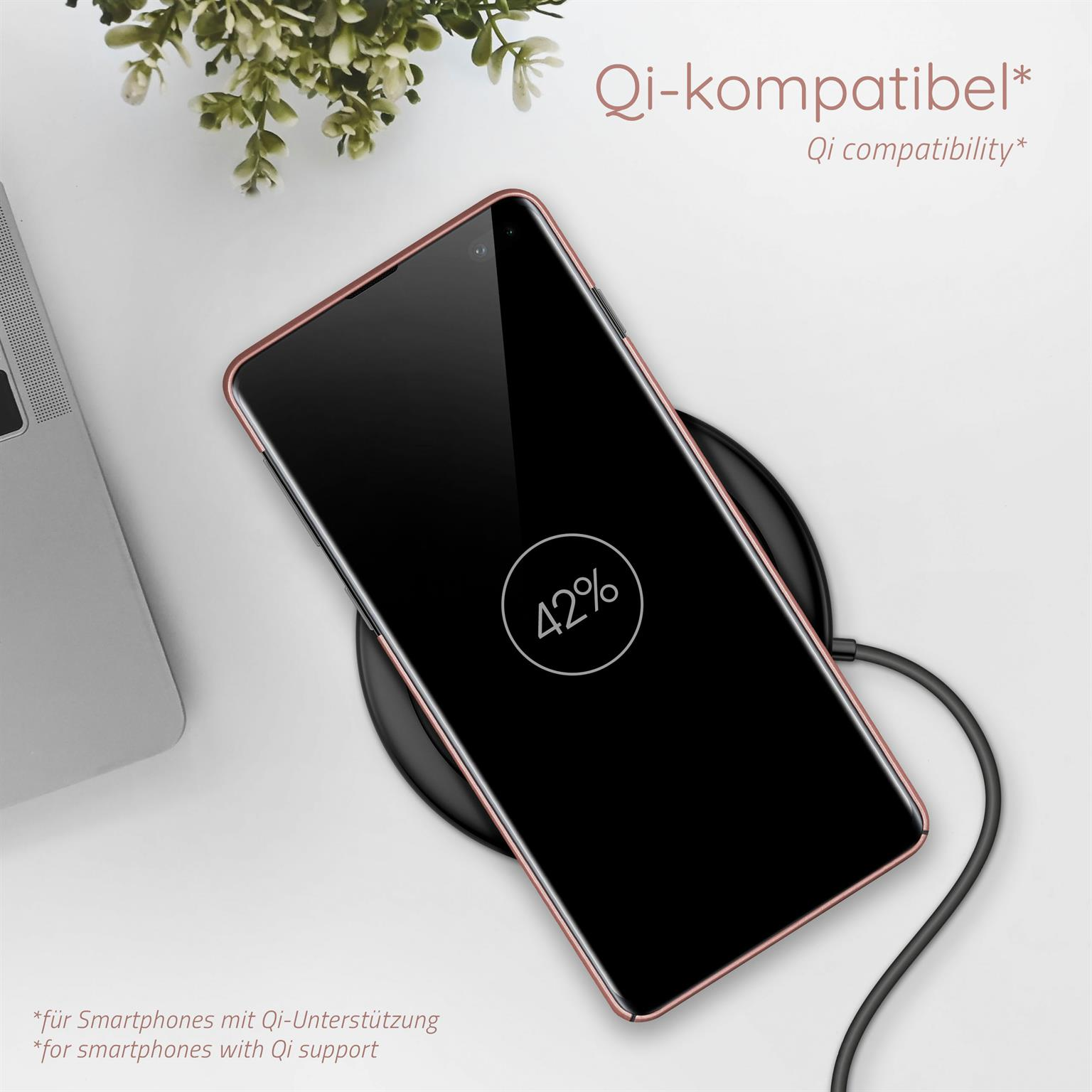 Telefon lädt auf einem kabellosen Ladegerät, mit Pflanze und Laptop im Hintergrund.