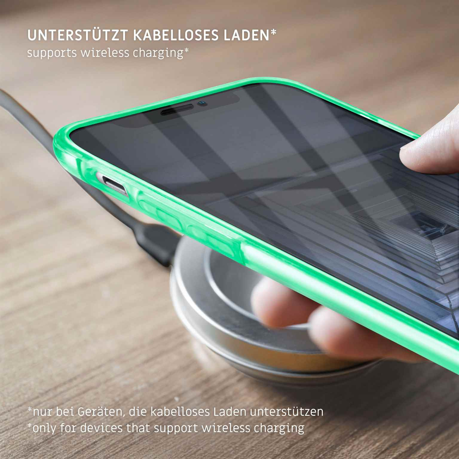 Eine grüne Handyhülle liegt auf einem kabellosen Ladegerät. Text weist auf kabelloses Laden hin. Der Hintergrund ist unscharf.
