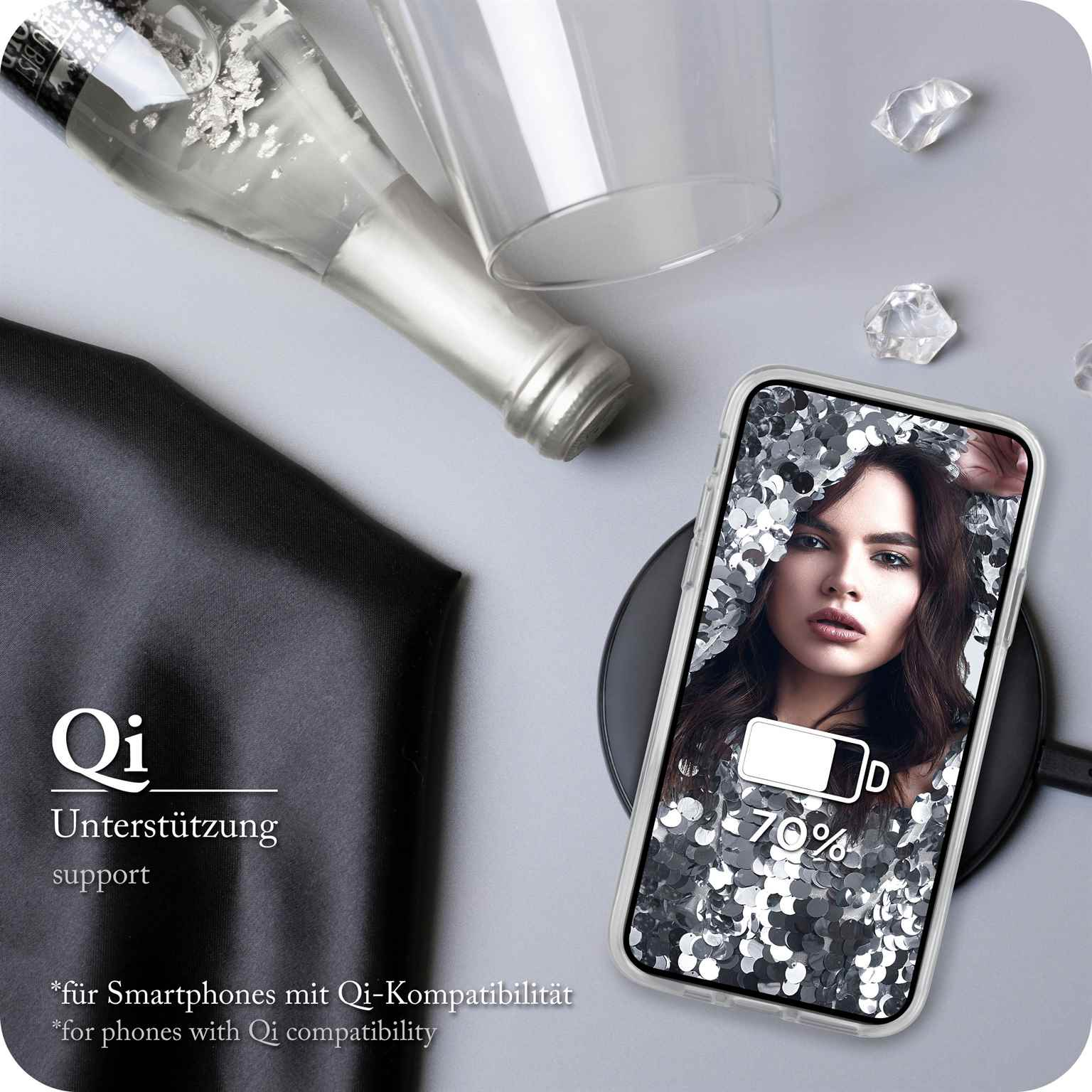 Telefon mit Model auf kabellosem Ladegerät. Champagnerflasche, Glas und schwarzer Stoff auf grauer Oberfläche.
