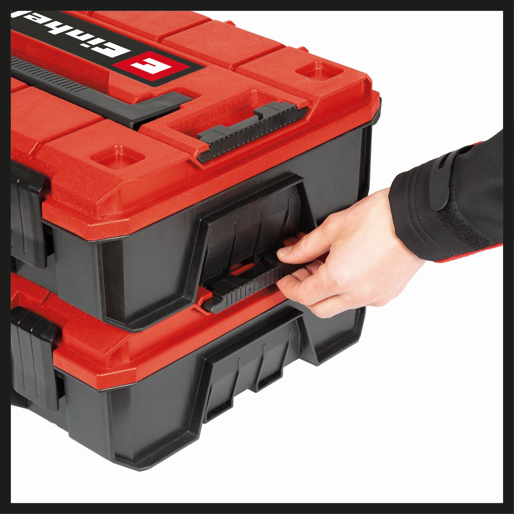 Die Hand einer Person öffnet eine rot-schwarze Werkzeugkiste mit zwei Abschnitten.