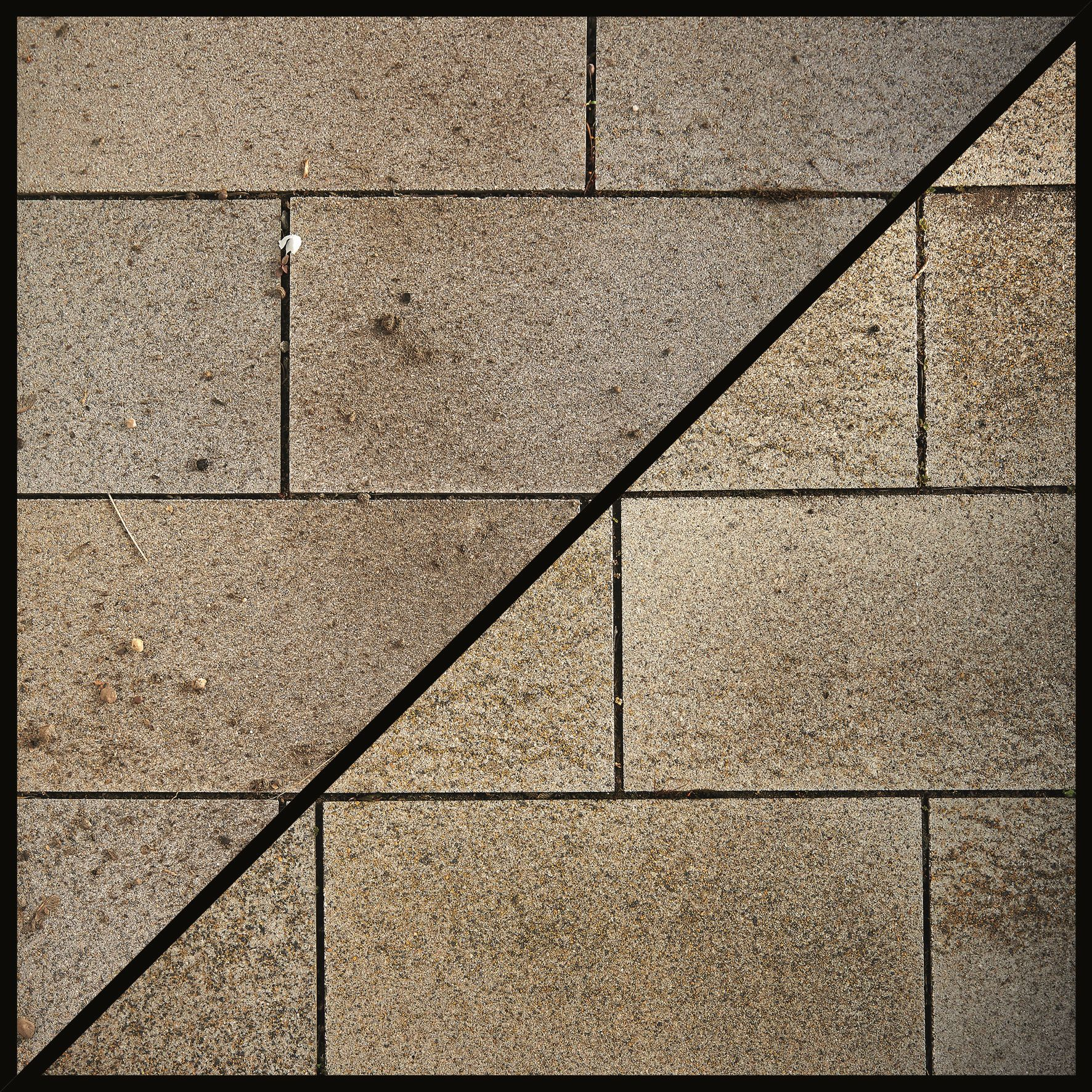 Geflieste Steinoberfläche, geteilt durch eine schwarze Diagonale.