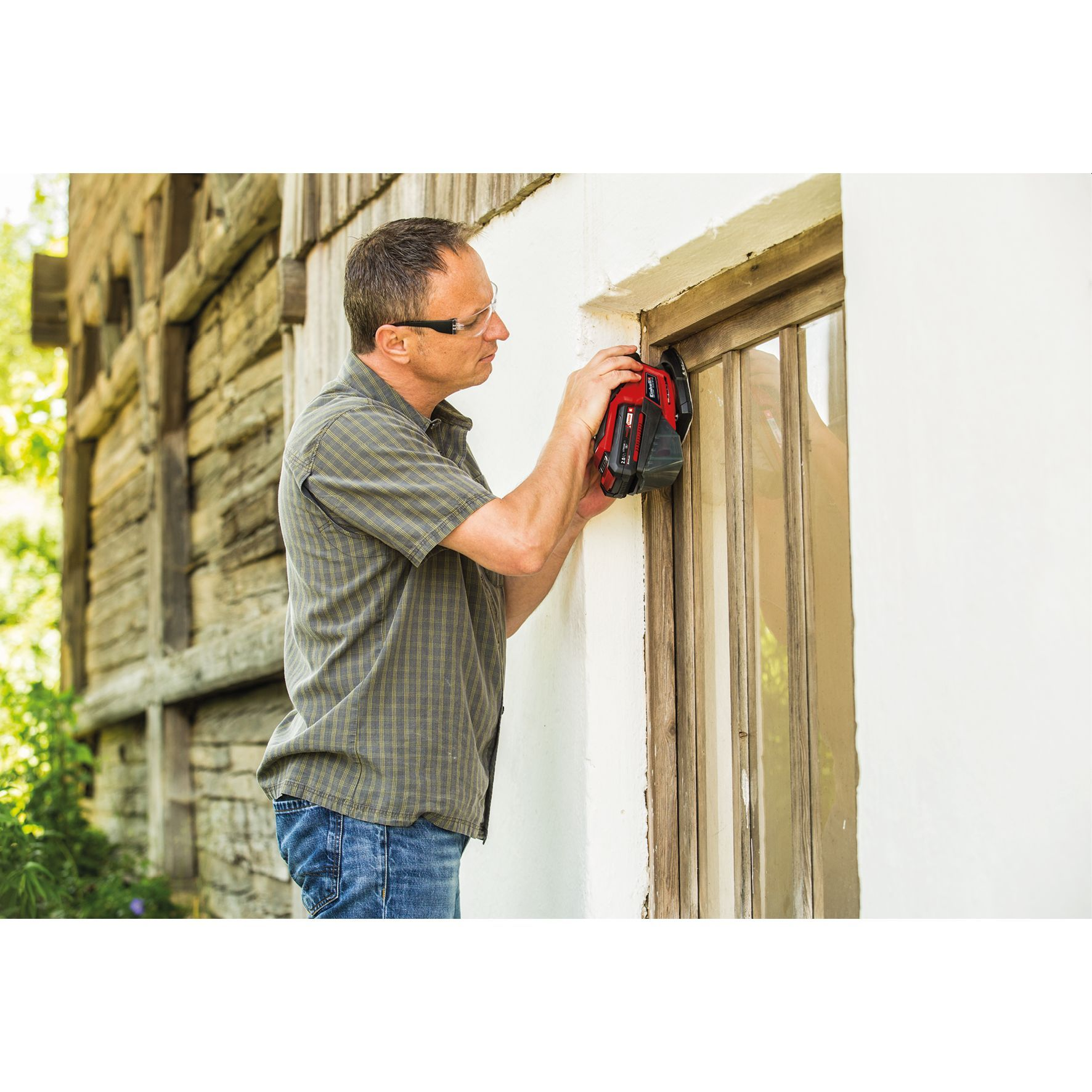 Mann repariert etwas in der Nähe eines Fensters. Weiße Wand und Holzgebäude.