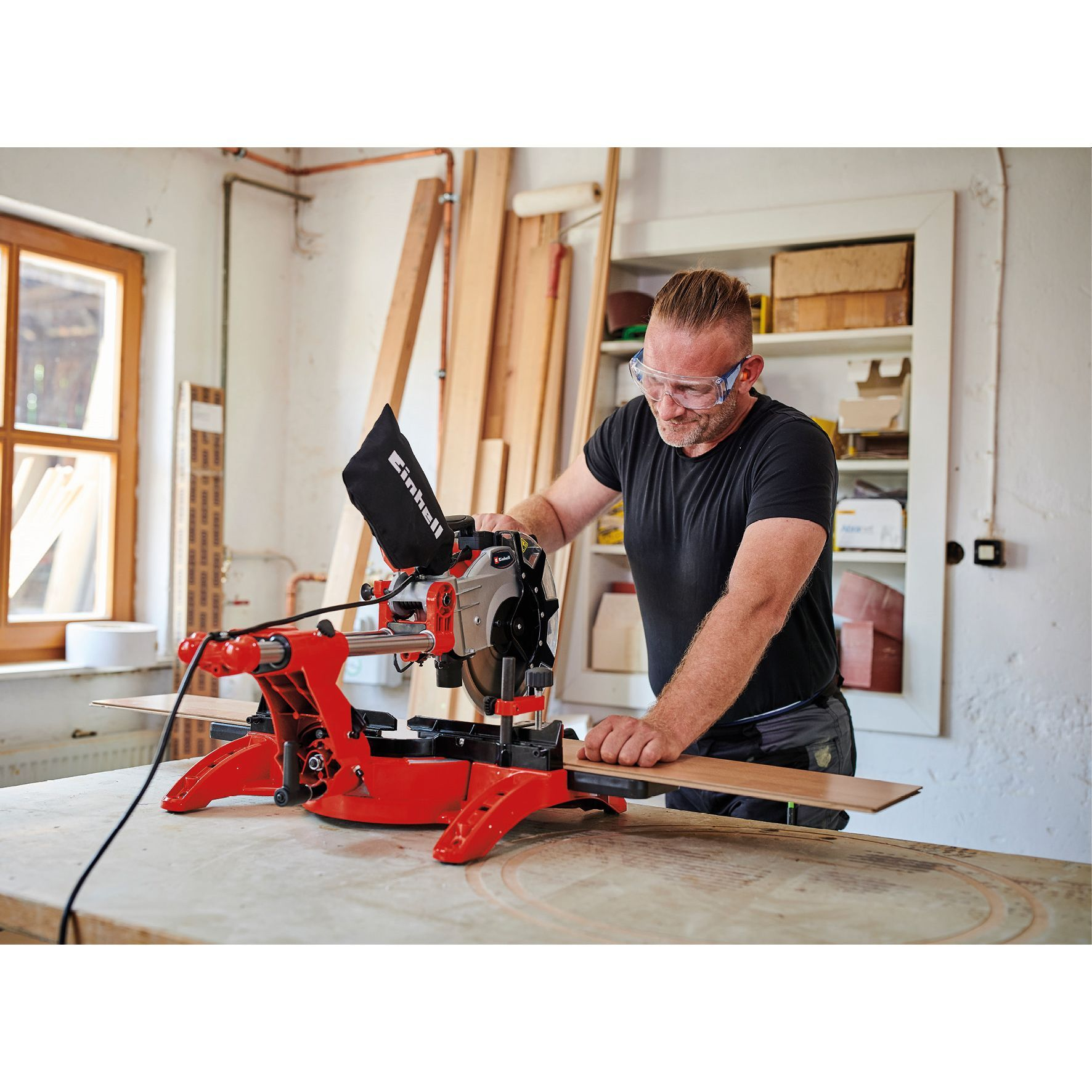Mann benutzt rote Kreissäge, um Holz zu schneiden. Werkstatteinstellung.