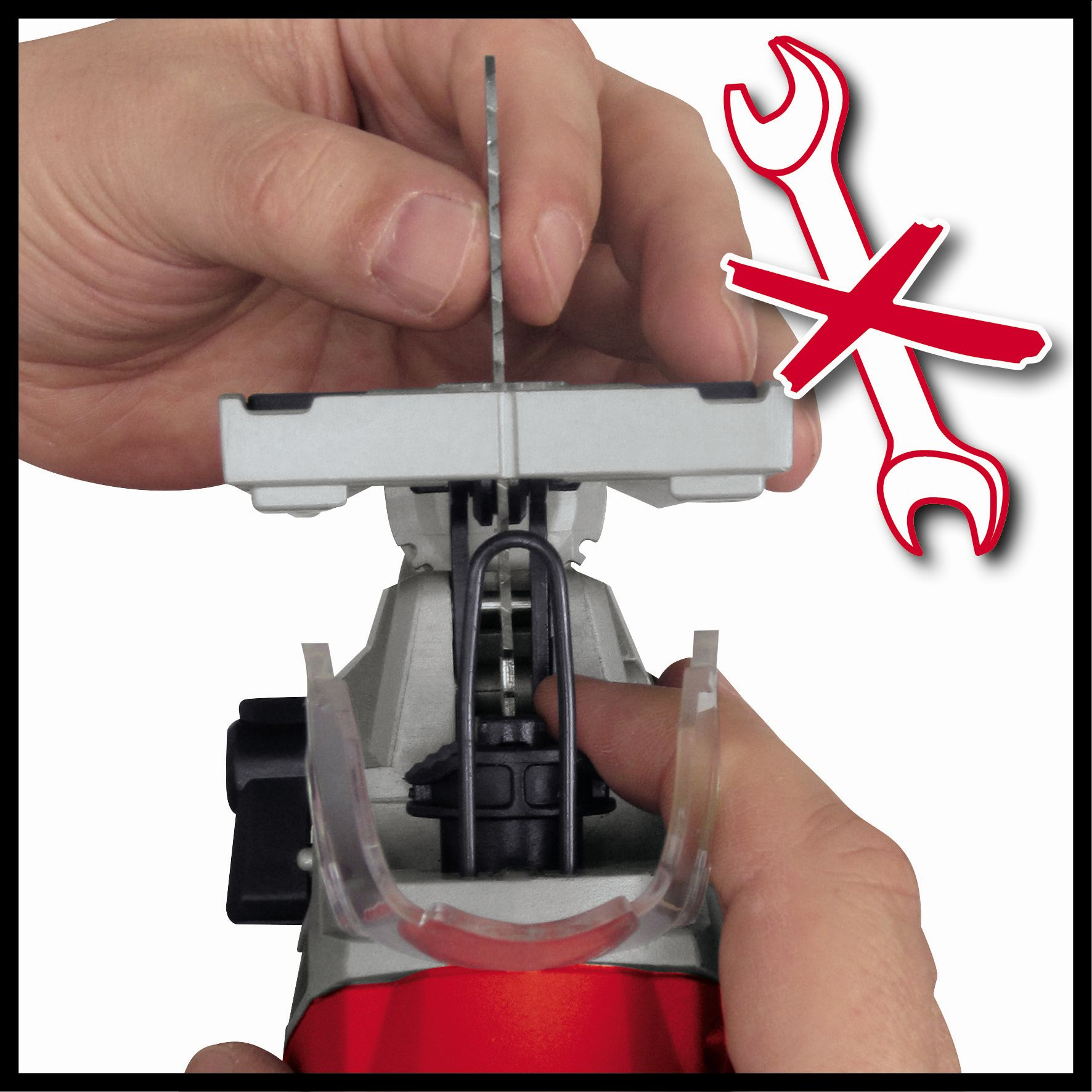 Ręce wkładające brzeszczot do wyrzynarki. Czerwony klucz z krzyżem w rogu.