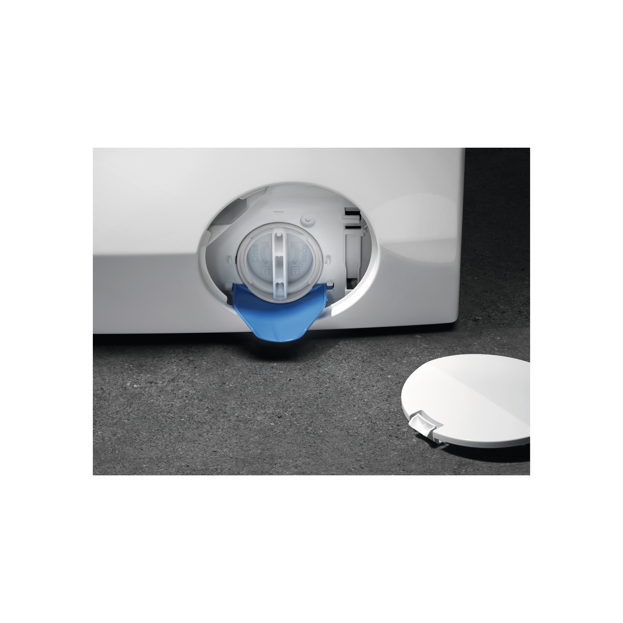 Zbliżenie białej pralki. Komora filtra jest otwarta.