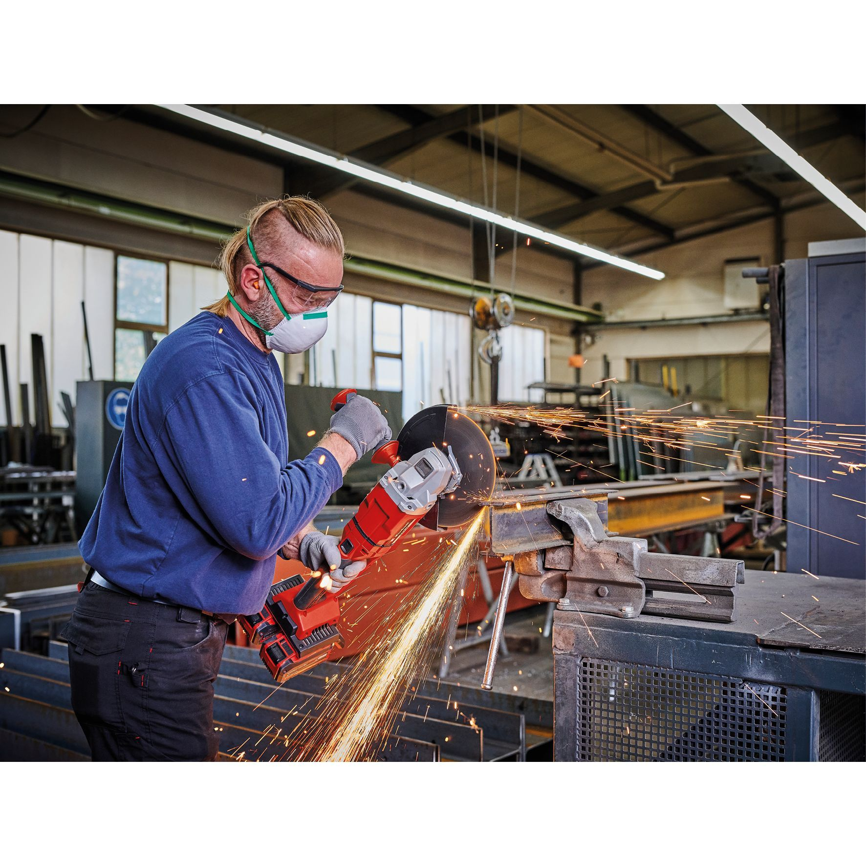 Mężczyzna używający szlifierki kątowej, w masce i okularach ochronnych.