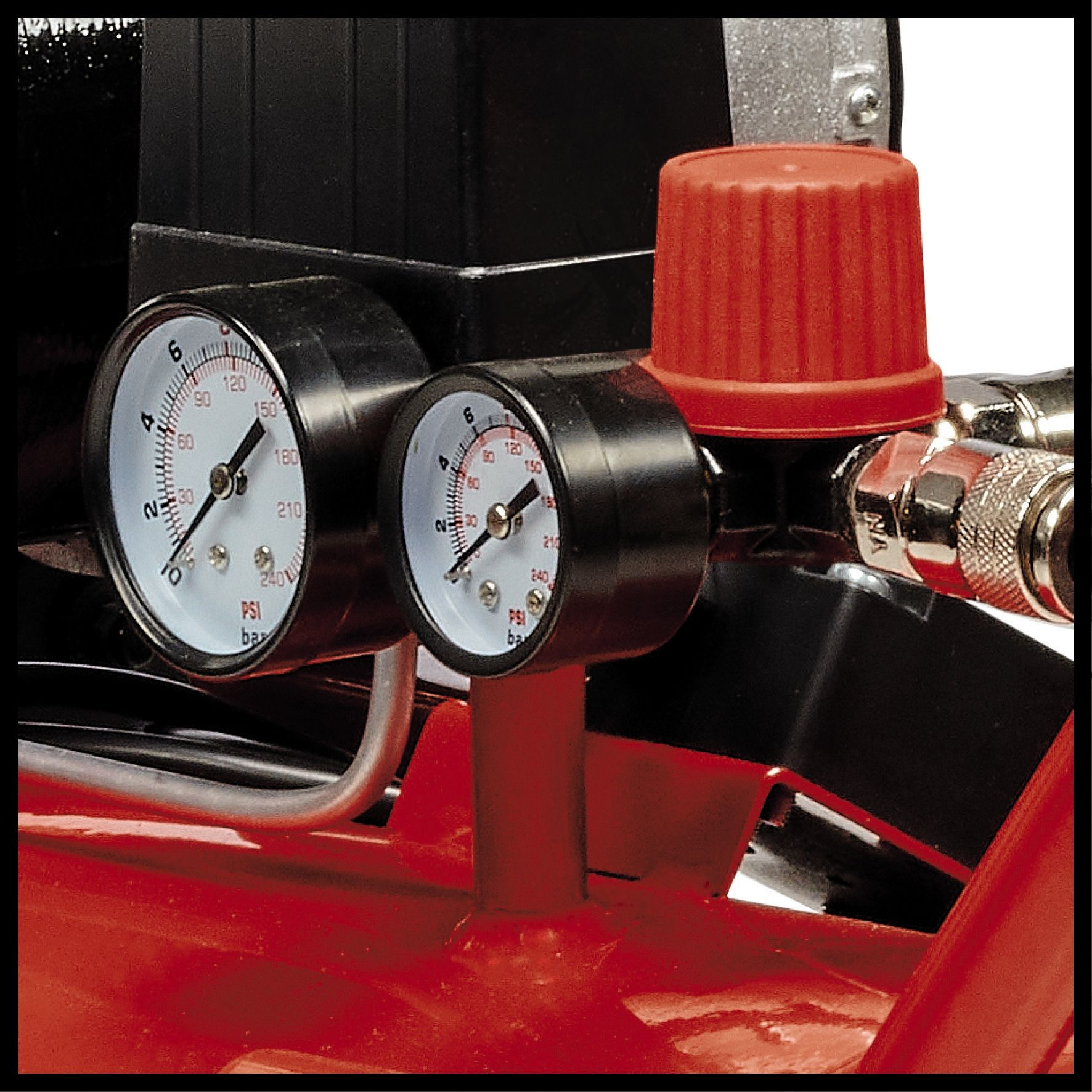 Zwei Manometer an einem Luftkompressor mit einem roten Knopf oben. Der Hintergrund ist rot.
