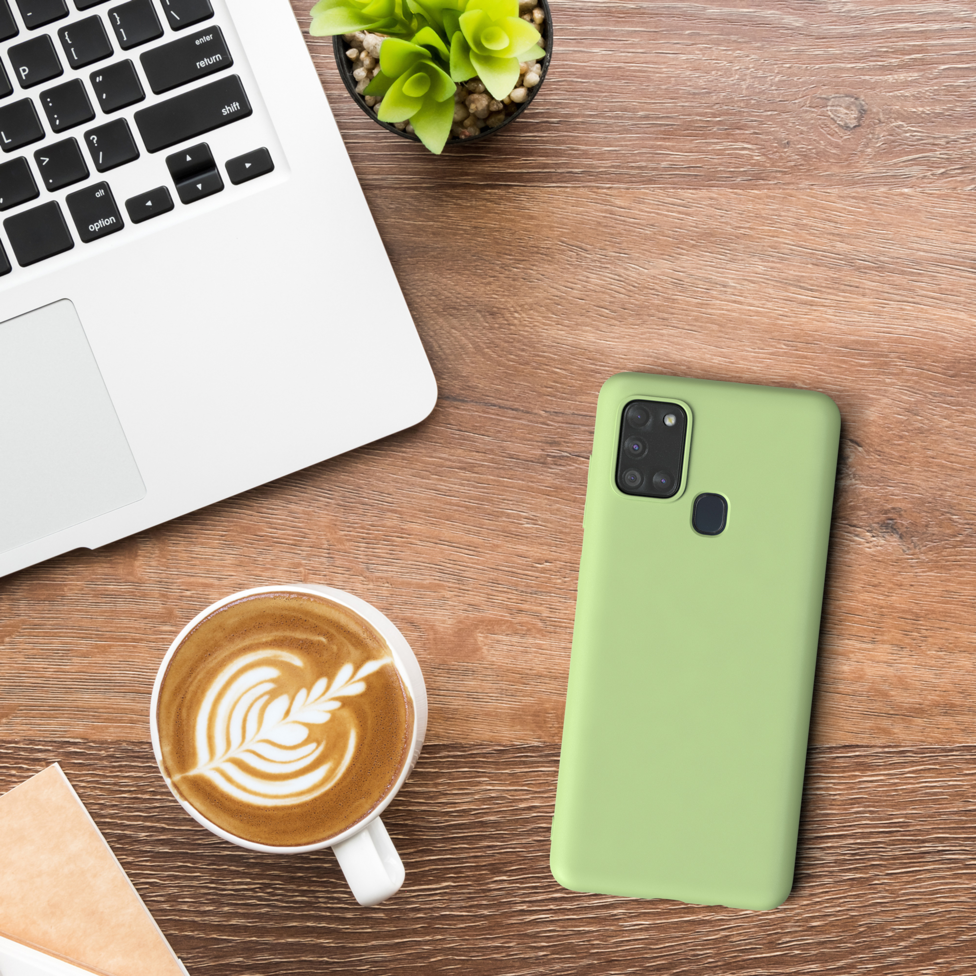 Ein Telefon in einer Hülle, eine Tasse Kaffee und ein Laptop auf einem Holztisch.