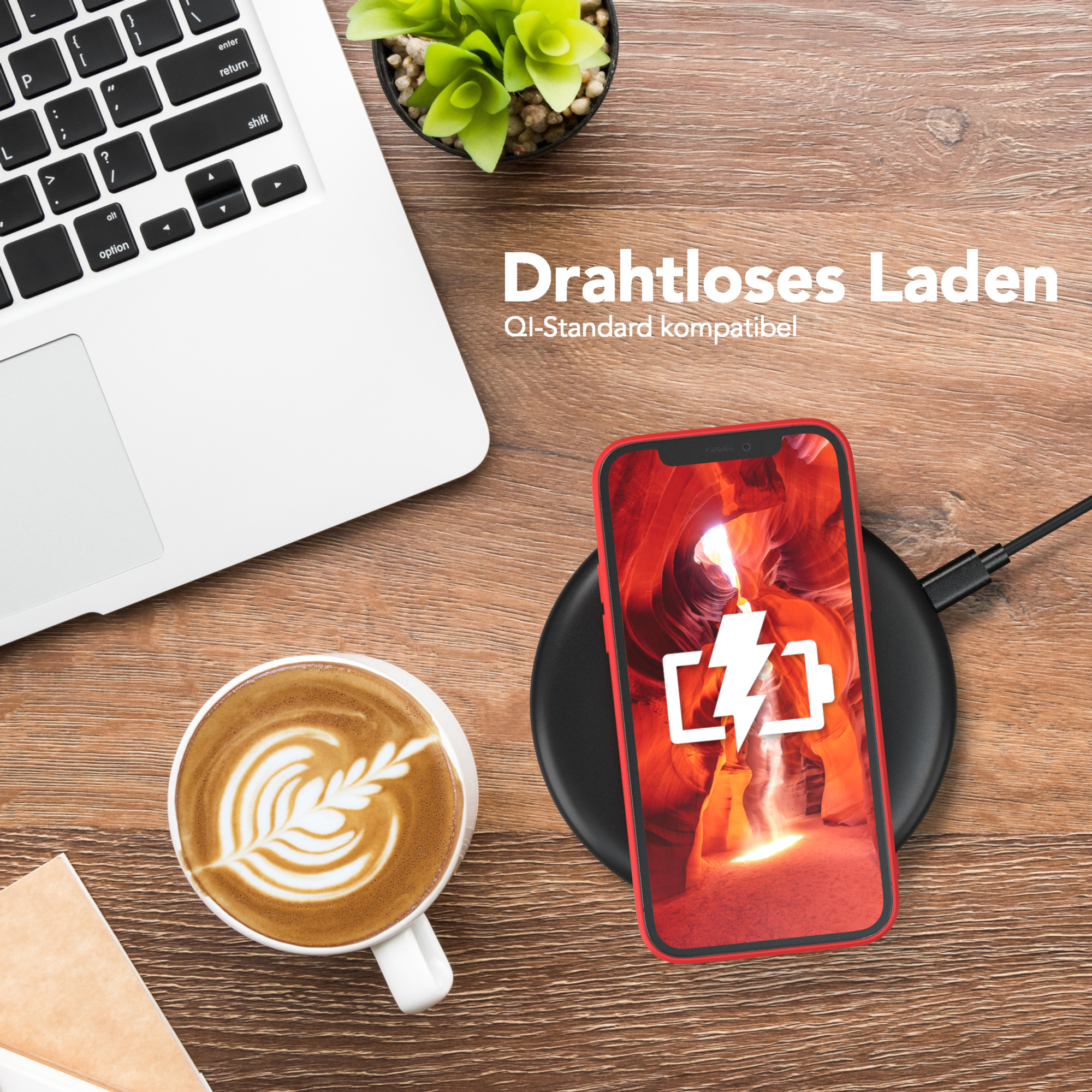Ein Telefon auf einem kabellosen Ladegerät. Auf einem Holztisch befinden sich eine Kaffeetasse und ein Laptop.