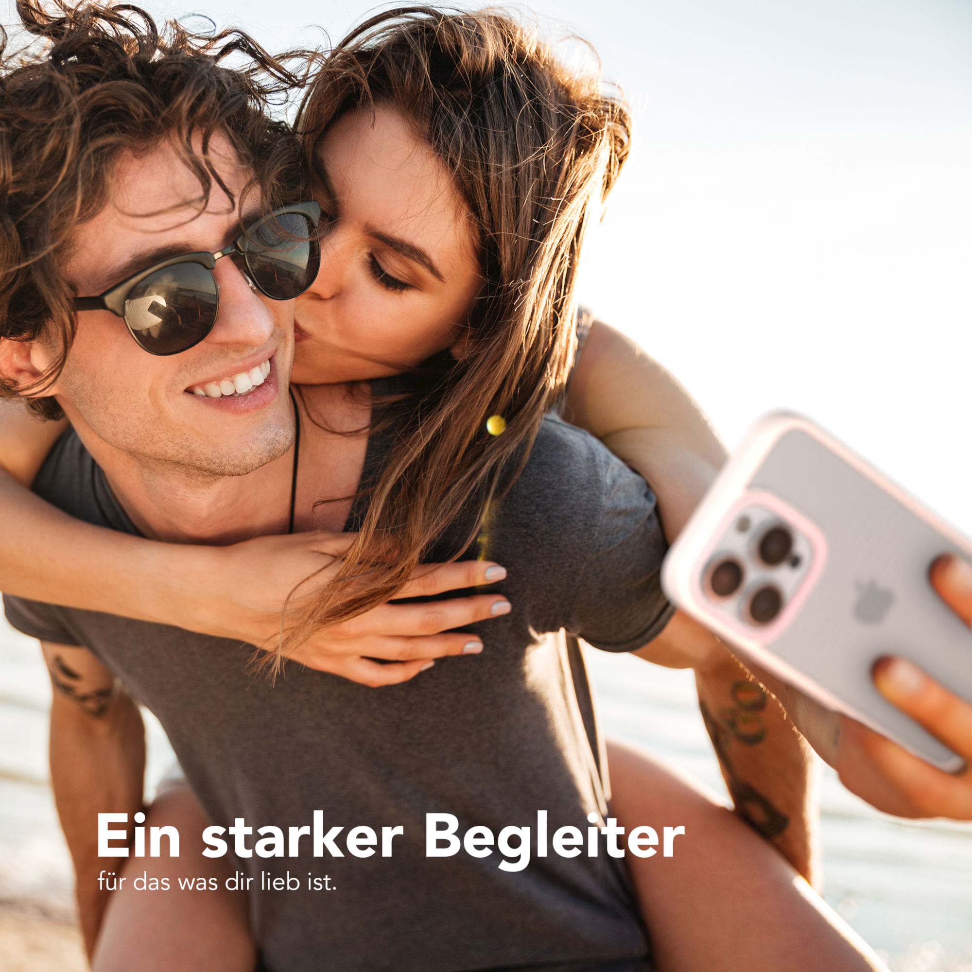 Ein Paar macht ein Selfie. Die Frau küsst den Mann. Er lächelt.