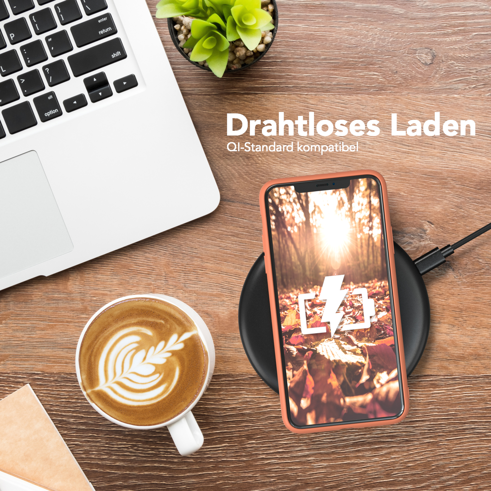 Telefon auf kabellosem Ladegerät, Kaffee, Laptop, Pflanze auf Holzschreibtisch. Ladesymbol auf dem Bildschirm.