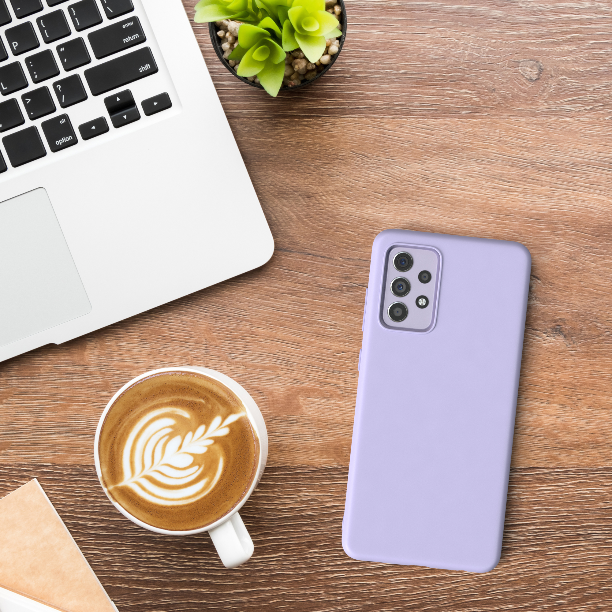 Eine lila Handyhülle auf einem Holztisch mit einem Laptop und einer Kaffeetasse.