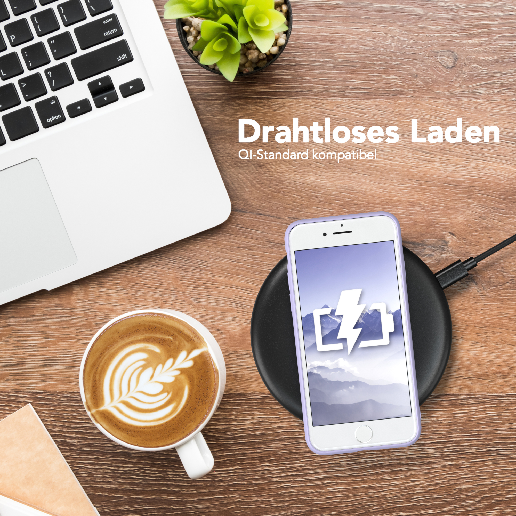 Ein Laptop, eine Kaffeetasse mit Latte Art und ein Telefon auf einem kabellosen Ladegerät.