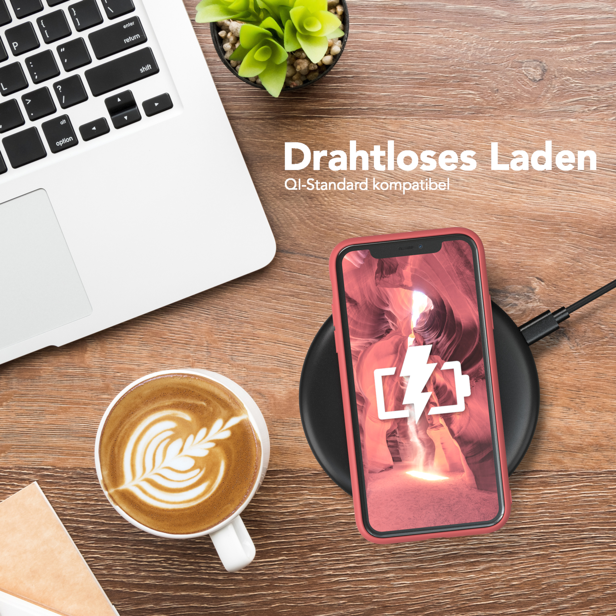 Ein Telefon, das drahtlos auf einem schwarzen Pad geladen wird, mit einer Kaffeetasse und einem Laptop.