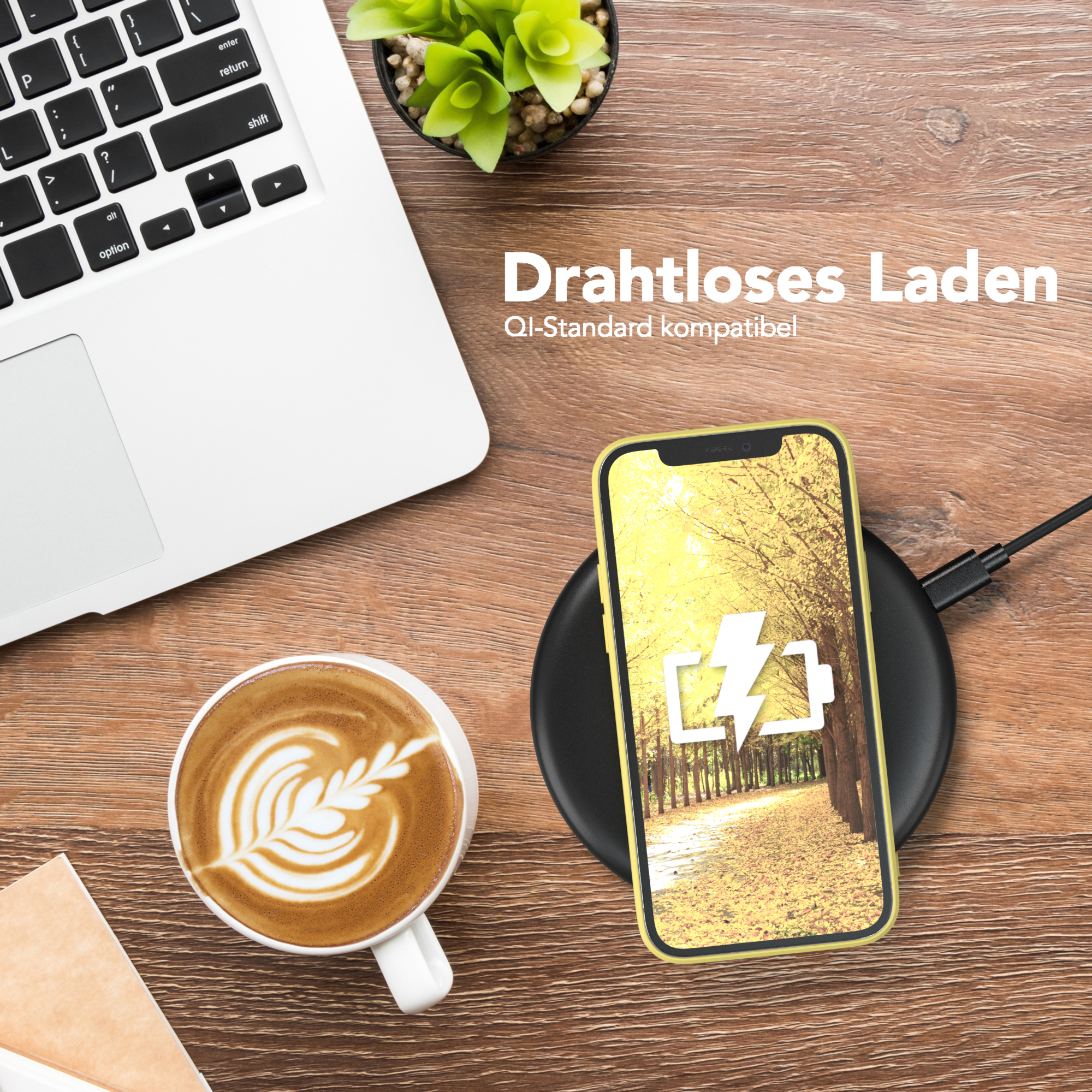 Ein Telefon, das auf einem kabellosen Ladegerät geladen wird, neben einer Tasse Kaffee und einem Laptop.
