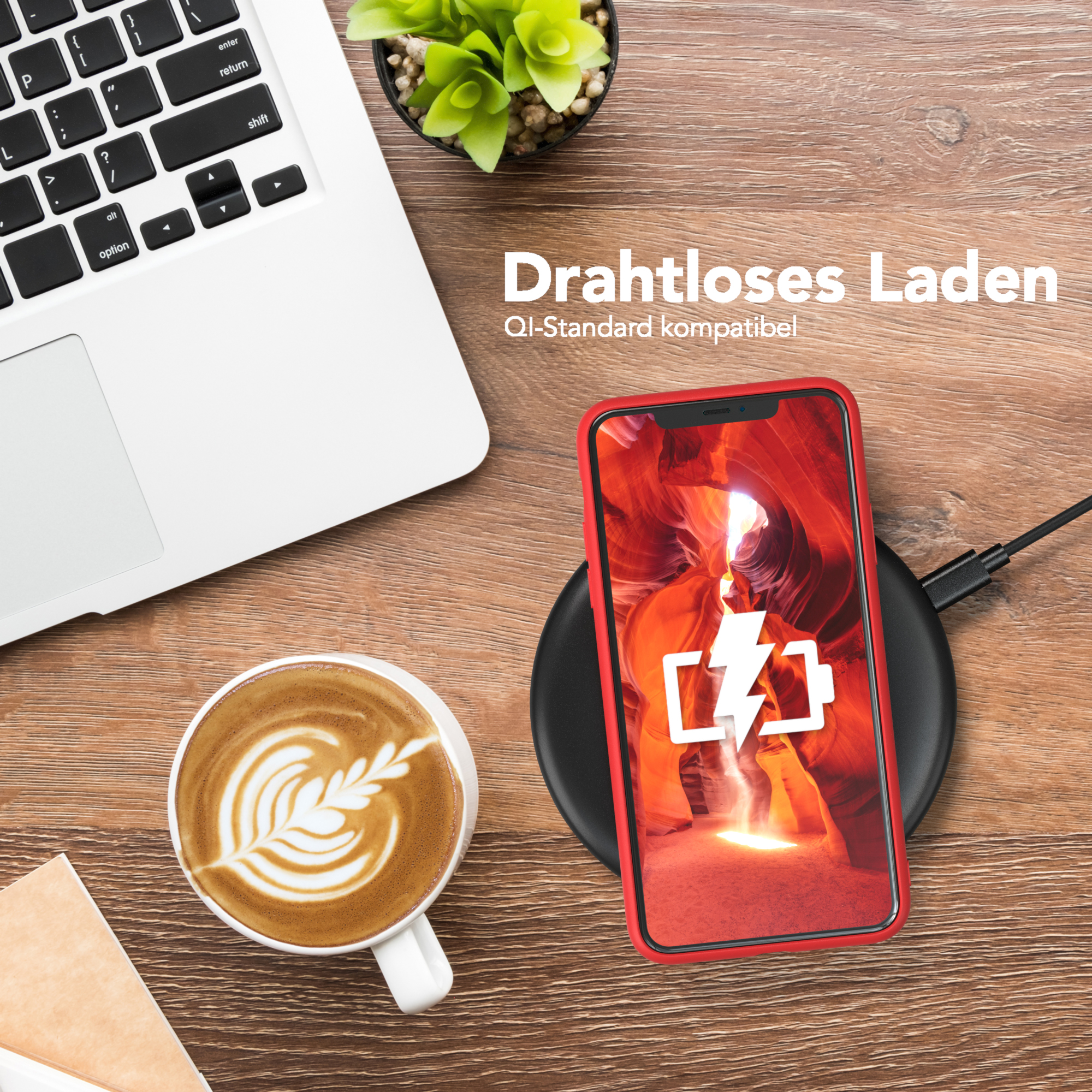 Telefon wird auf einem kabellosen Ladegerät aufgeladen. Laptop und Kaffeetasse stehen auf dem Tisch. Rote Handyhülle.