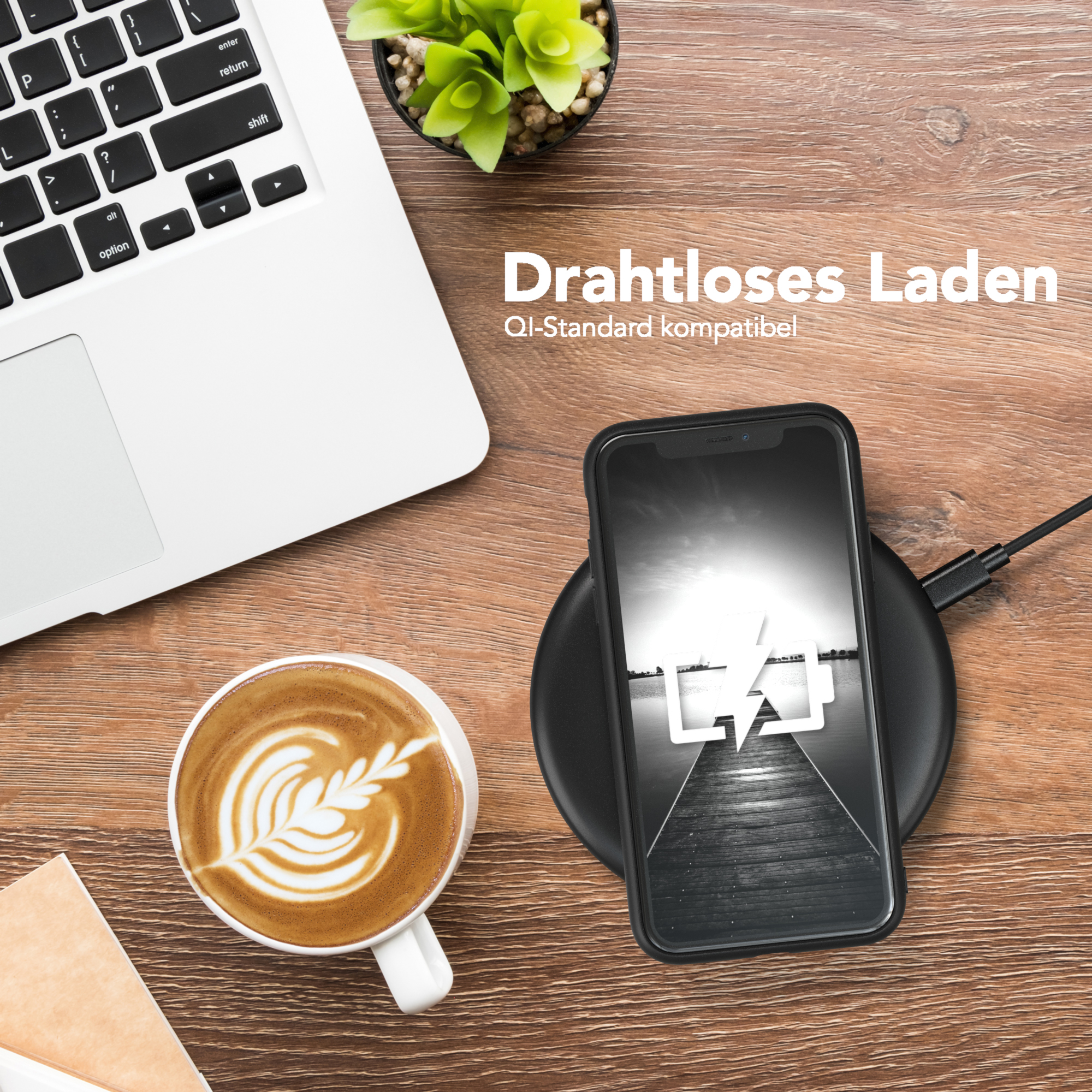 Laptop, Kaffee und Telefon auf einem Holztisch. Telefon auf kabellosem Ladegerät, Ladesymbol sichtbar.