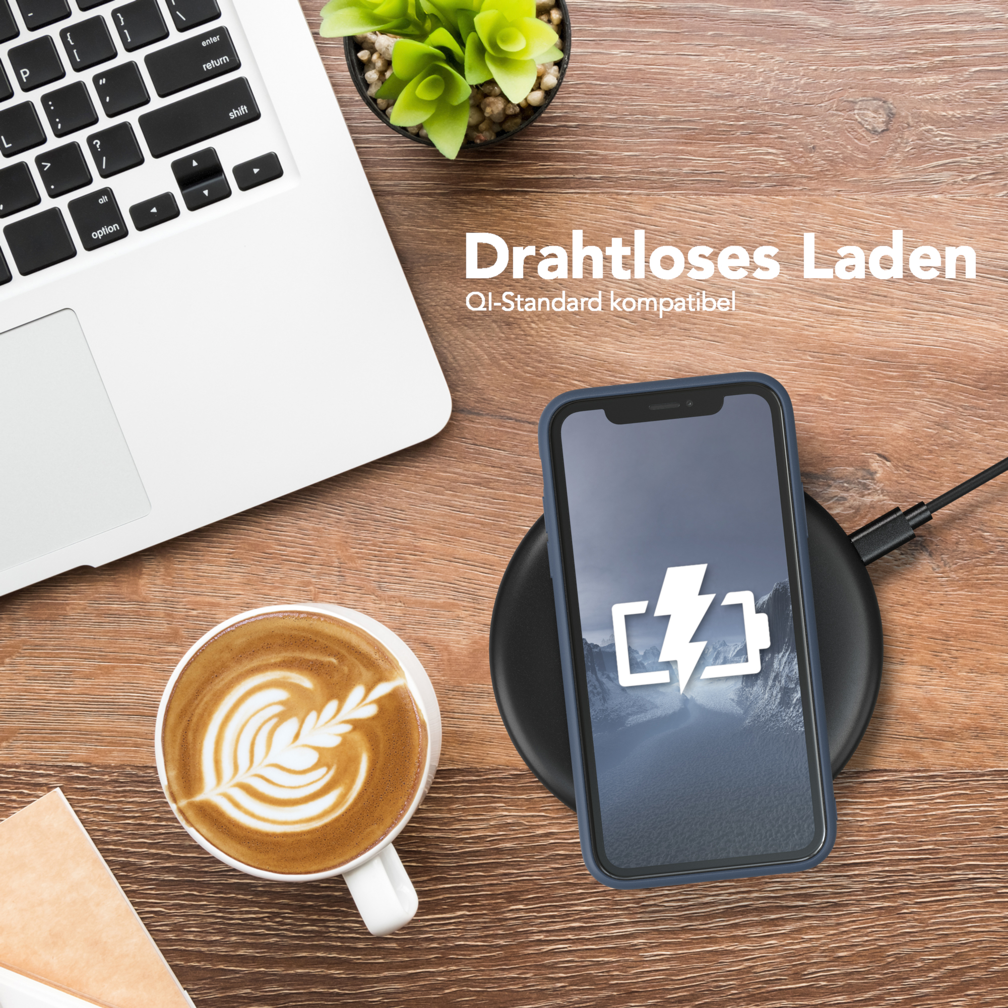 Telefon wird drahtlos auf einem Pad geladen. Ein Laptop und Kaffee stehen auf dem Tisch.