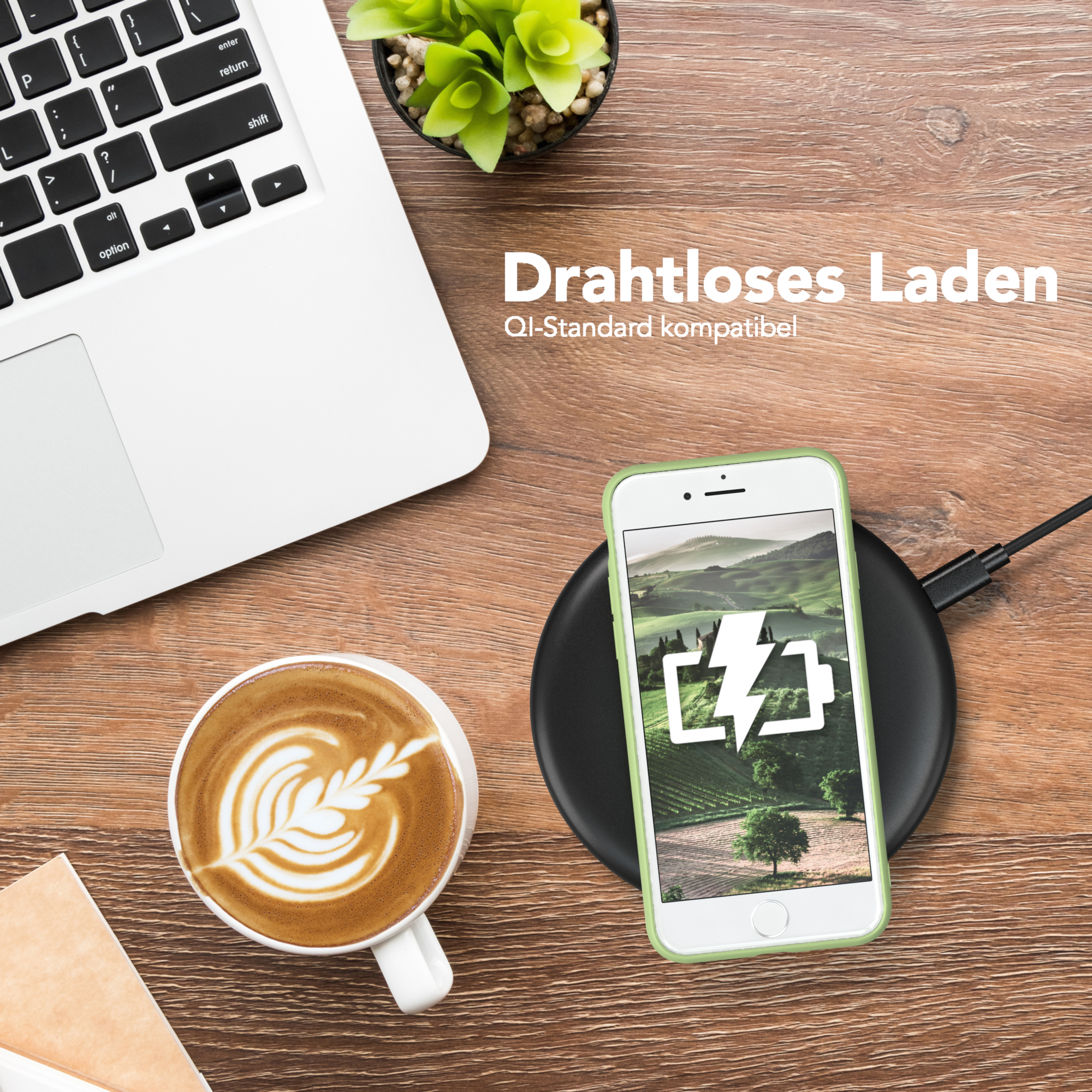 Telefon wird auf einem kabellosen Ladegerät aufgeladen. Laptop und Kaffeetasse stehen auf dem Tisch. Grüne Handyhülle.
