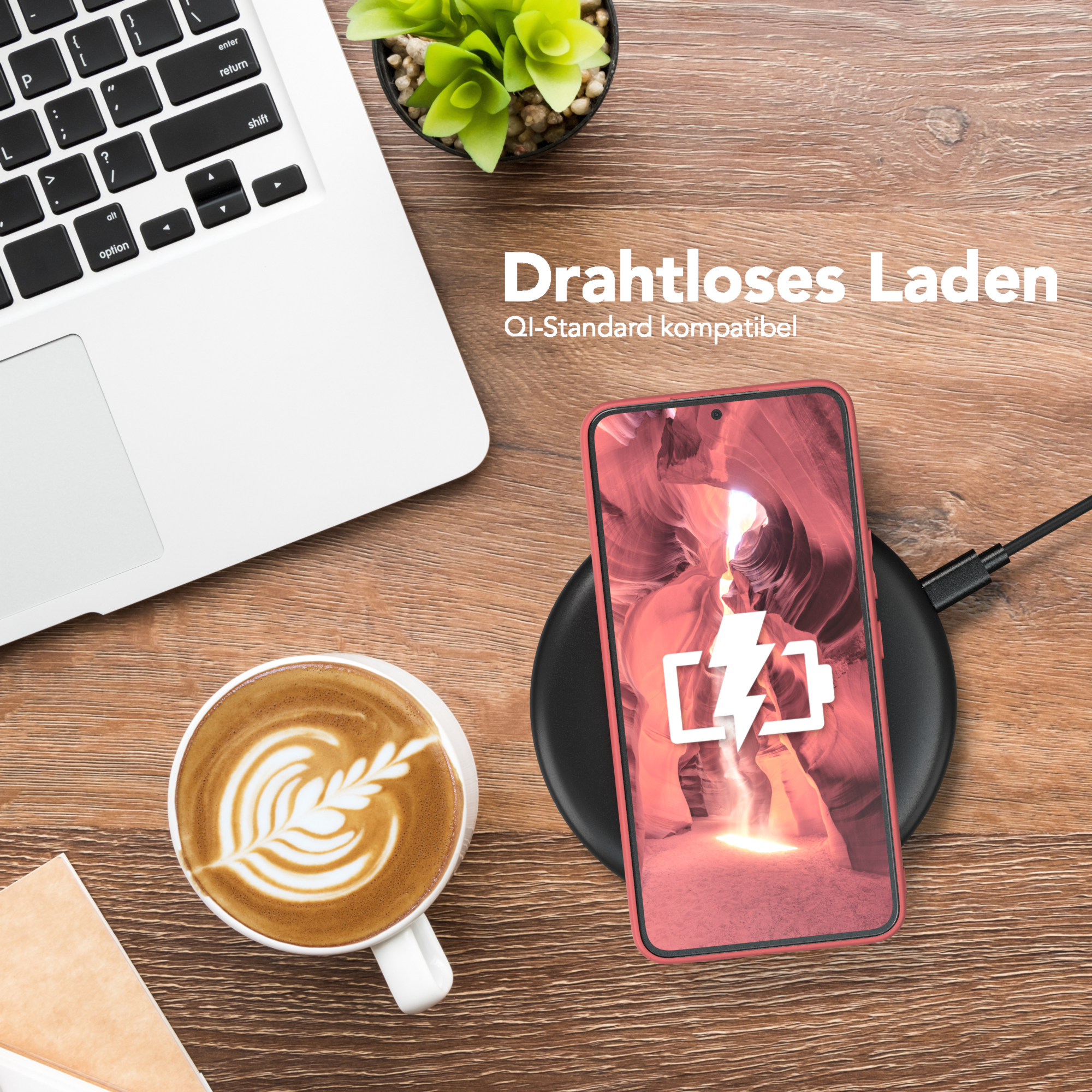 Laptop, Kaffee, Telefon auf kabellosem Ladegerät. Telefon zeigt Ladesymbol.