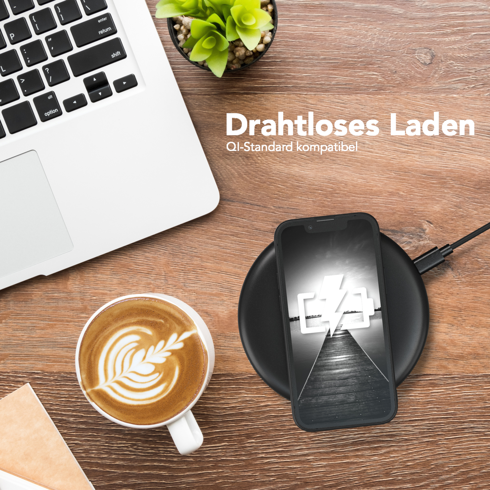 Ein Telefon, das auf einem kabellosen Ladegerät geladen wird, neben einem Laptop und einer Tasse Kaffee.