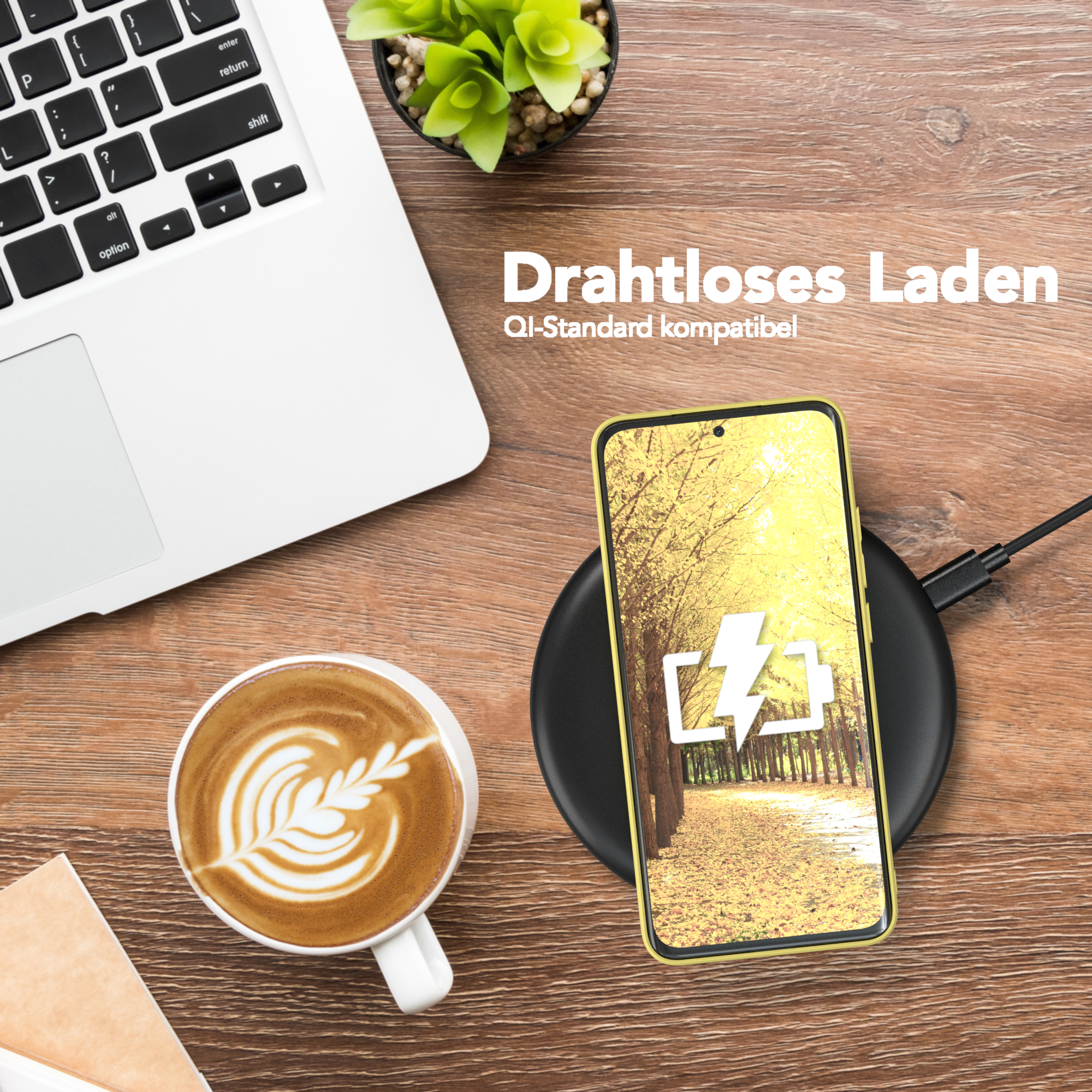 Ein Telefon wird drahtlos auf einem schwarzen Pad aufgeladen. Eine Kaffeetasse und ein Laptop sind auf einem Holztisch.