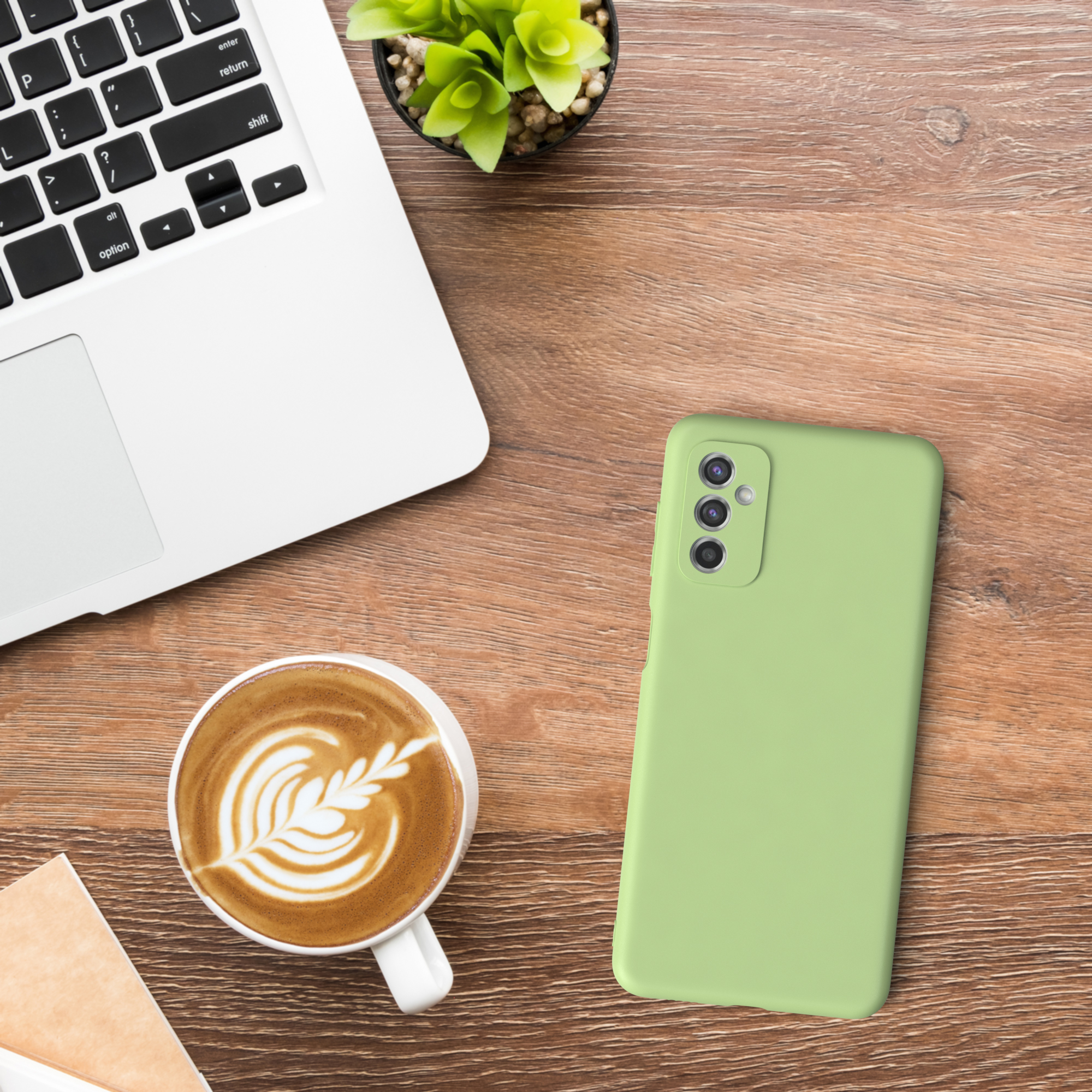 Laptop, Kaffee und grüne Handyhülle auf Holztisch.