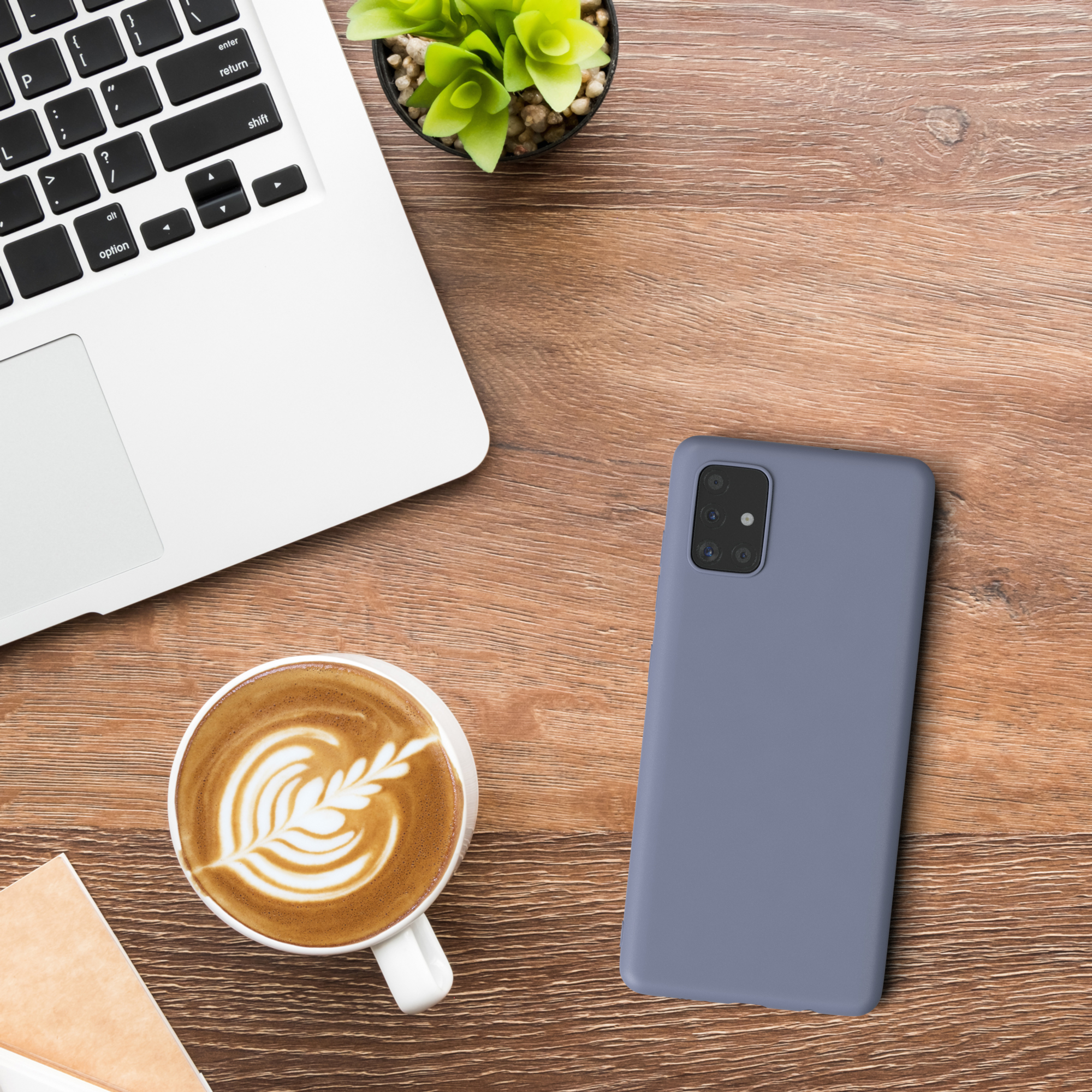 Laptop, Kaffeetasse, Pflanze und Telefon. Telefon und Hülle sind blau. Auf Holz.